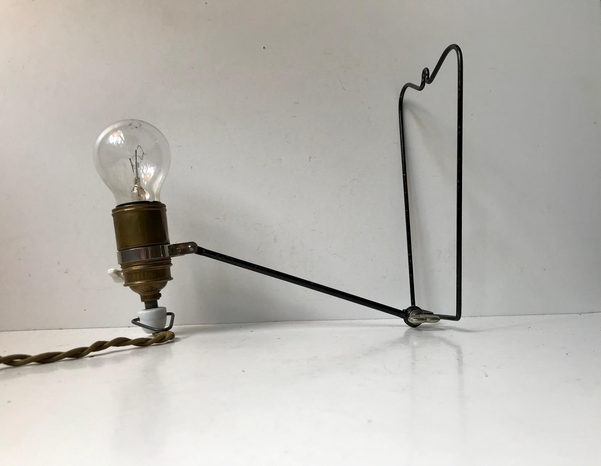 Petite lampe de table ou murale en fil métallique d'aspect industriel minimal, dans son état brut d'origine. Il est réglable et peut être suspendu comme une applique murale ou utilisé comme une petite lampe de bureau minimale. Il comporte un