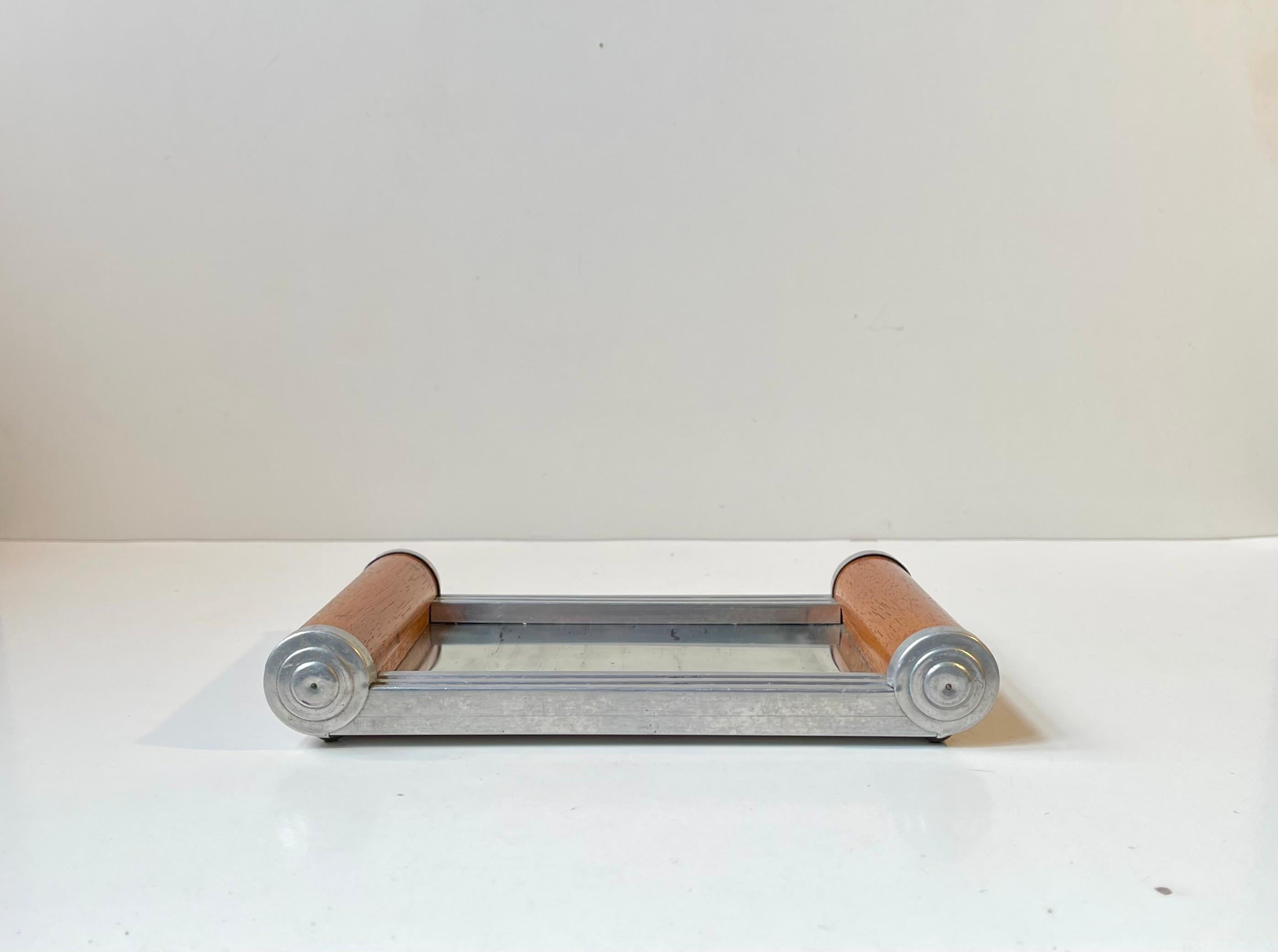 Una pequeña bandeja de espejo aerodinámico o espejo de meseta. Originalmente se utilizaba con fines de vanidad, para joyas o incluso para preparar opio durante la década de 1930. Esta versión en concreto se fabricó en Alemania y presenta asas de