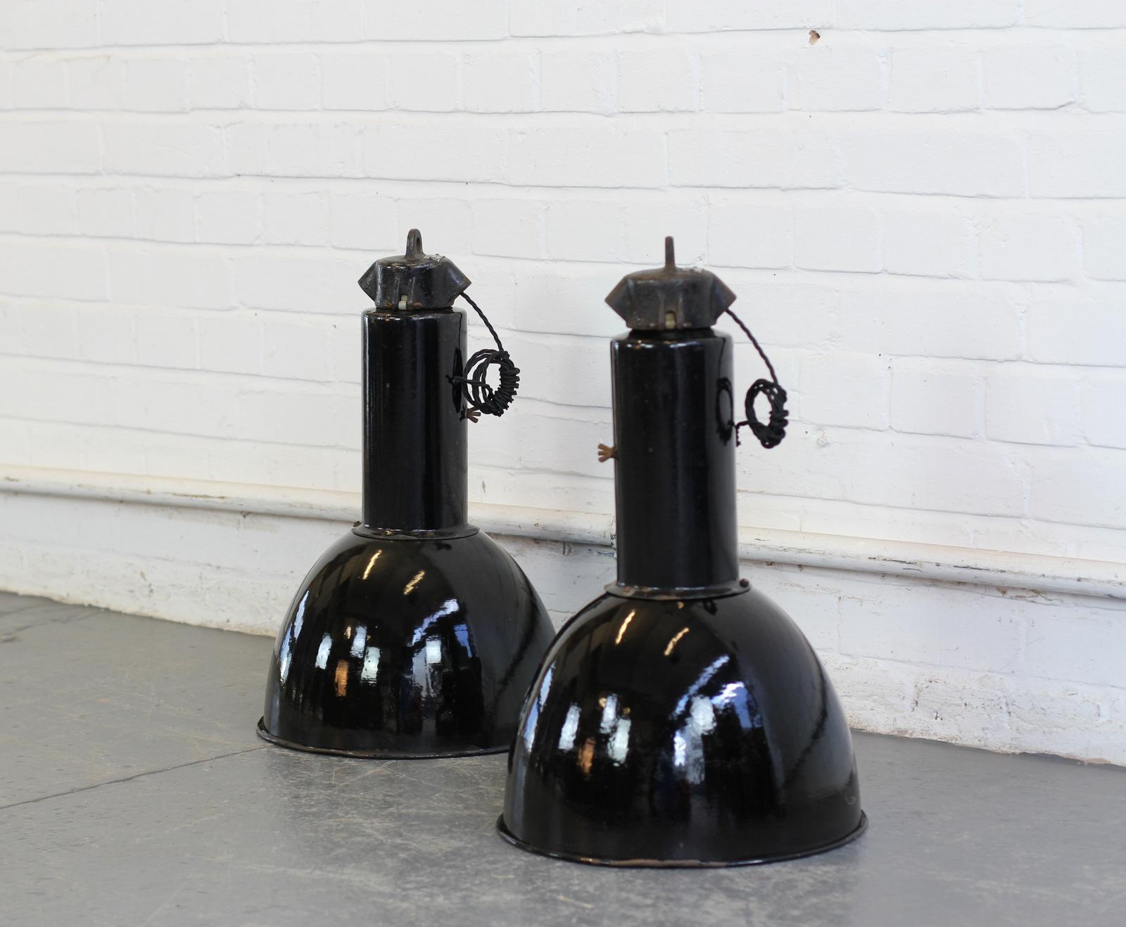 Bauhaus industrial pendant lights, circa 1930s.

- Price is per light (2 available)
- Vitreous black enamel with white enamel inner reflectors
- Cast iron tops
- Takes E27 fitting bulbs
- Comes with 100cm of black twist cable
- Comes with
