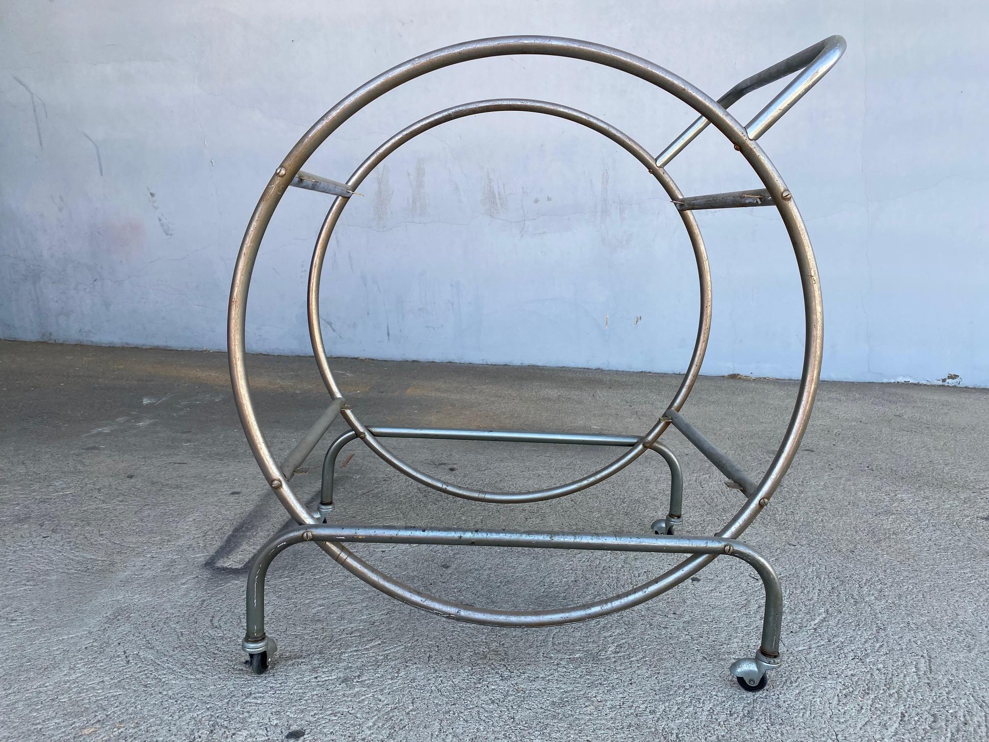 Streamlined Art Deco bar cart influenced heavily in its design by Bauhaus Modernism. Nickel tubing surrounds the top with glass shelving.