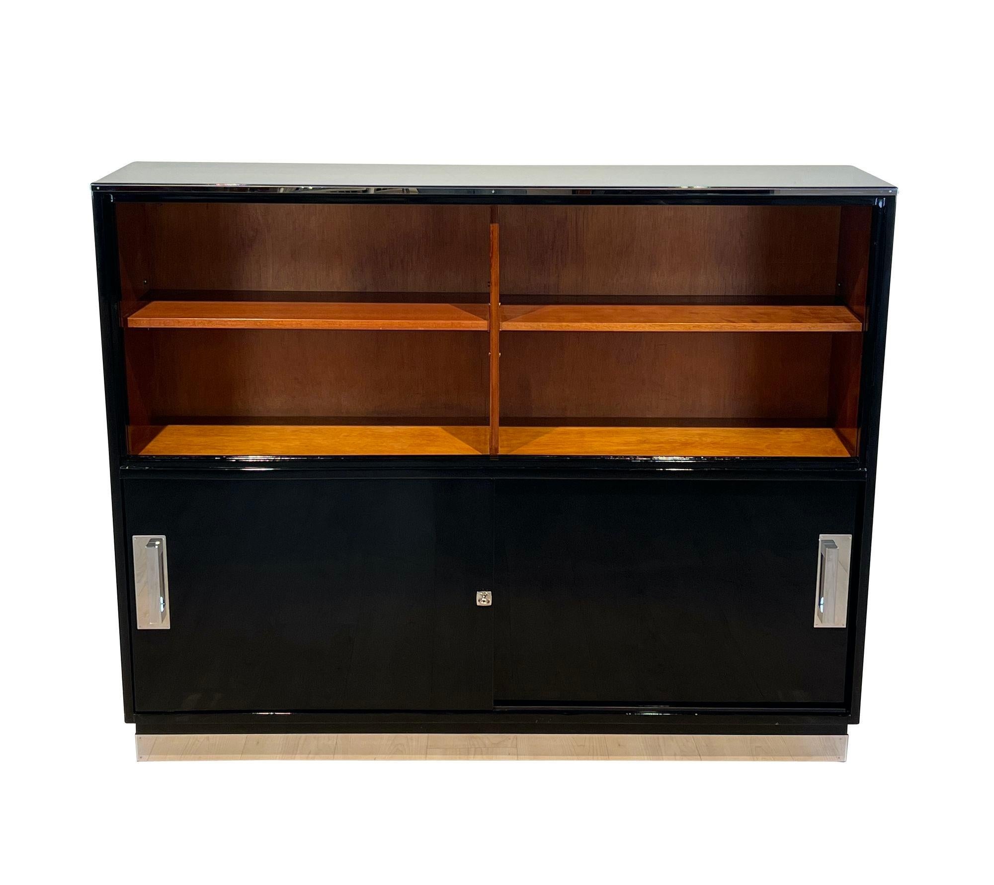 Elegant, cleanlined Bauhaus office wall cabinet or cupboard. Two available. Fully restored, from Germany circa 1930.
Black high gloss piano lacquer surface. Interior in mahogany, satin matte lacquered.
High stainless steel trim running around the