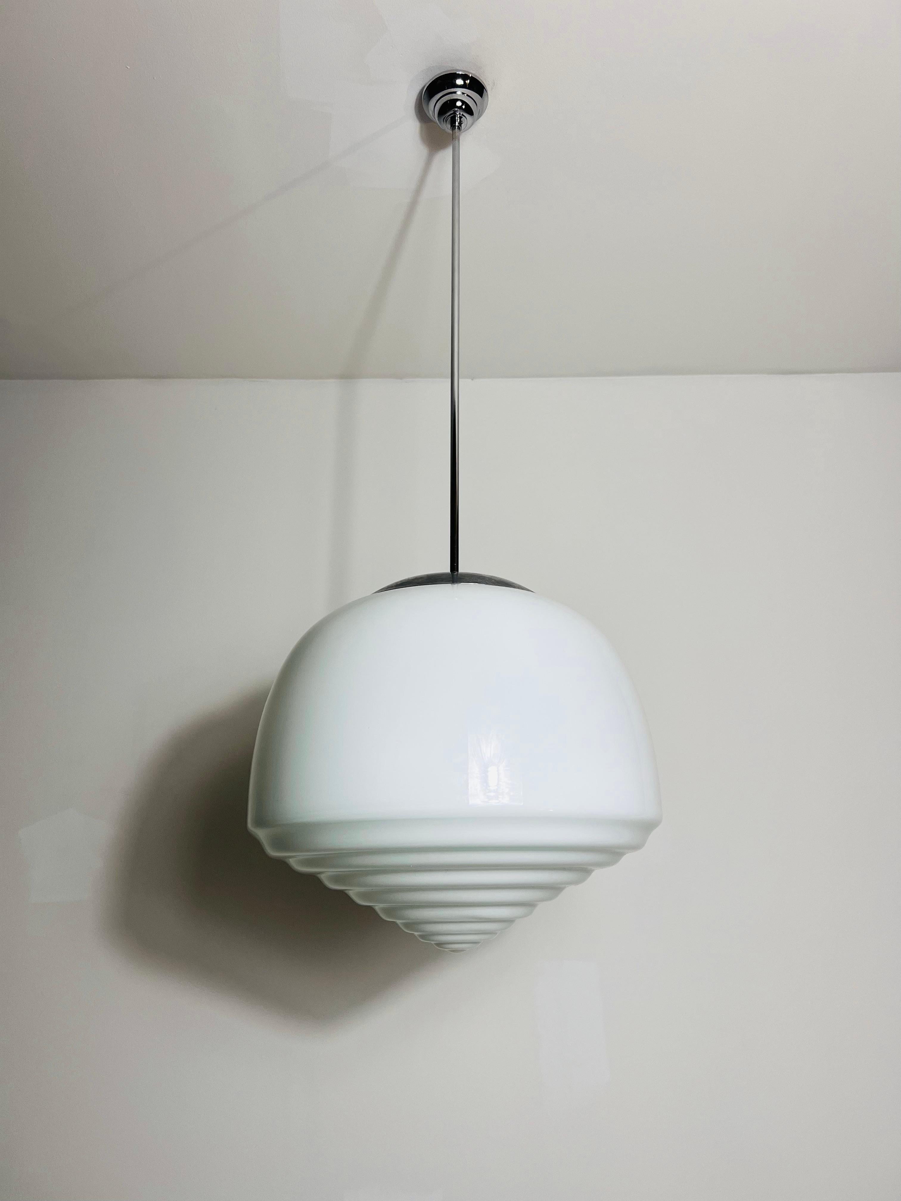 This Bauhaus lamp from the 1960s features a sleek and minimalist design, true to the principles of the Bauhaus movement. The lamp boasts a white opal glass shade that diffuses light beautifully, creating a soft and inviting glow. It is complemented