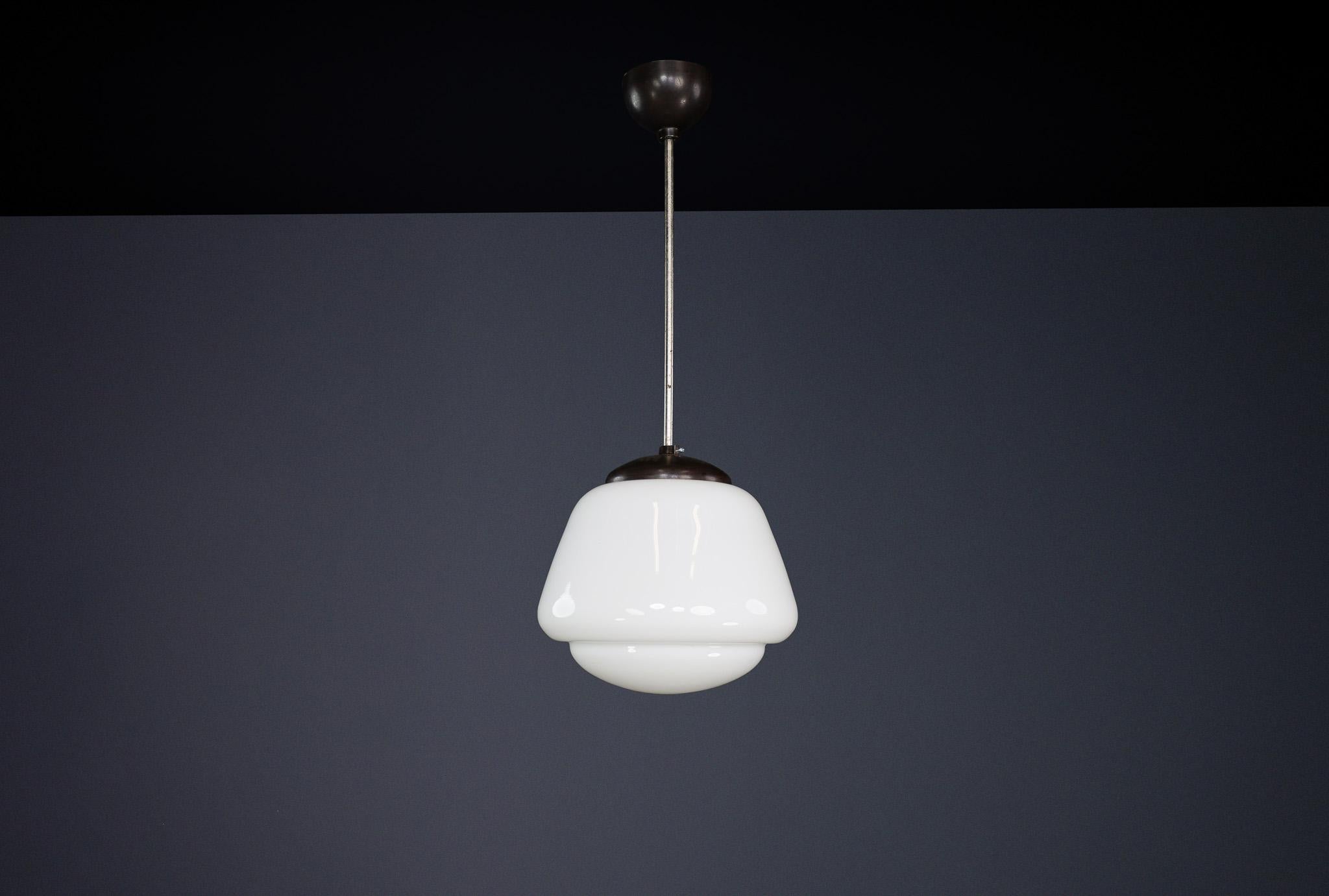 Bauhaus Opaline & Bakelite Pendant Lamp, Czech Republic 1950s

This elegant pendant lamp, designed in the 1950s in Czech Republic, is a striking example of Bauhaus influence on mid-century industrial design. It features a smooth, white opaline glass