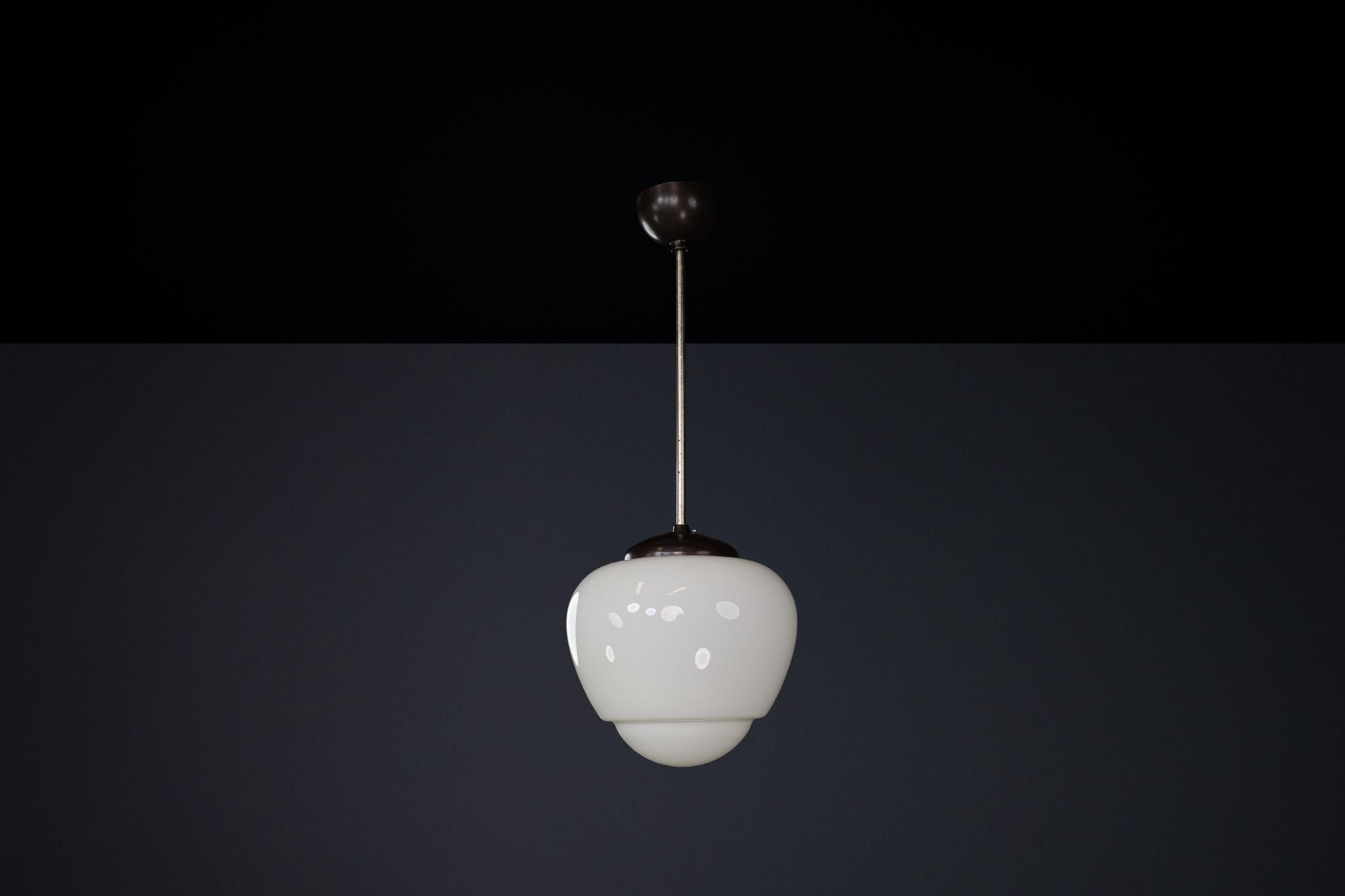 Bauhaus Opaline & Bakelite Pendant Lamp, Czech Republic 1950s

This elegant pendant lamp, designed in the 1950s in Czech Republic, is a striking example of Bauhaus influence on mid-century industrial design. It features a smooth, white opaline glass