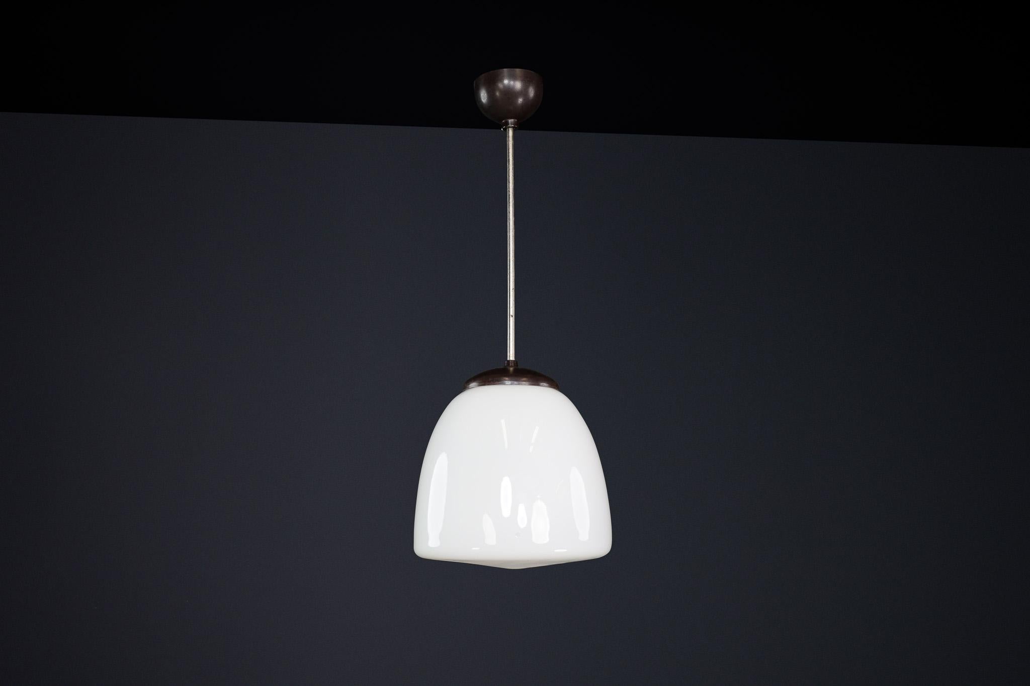 Bauhaus Opaline & Bakelite Pendant Lamp, Czech Republic 1950s

This elegant pendant lamp, designed in the 1950s in Czech Republic, is a striking example of Bauhaus influence on mid-century industrial design. It features a smooth, white opaline glass