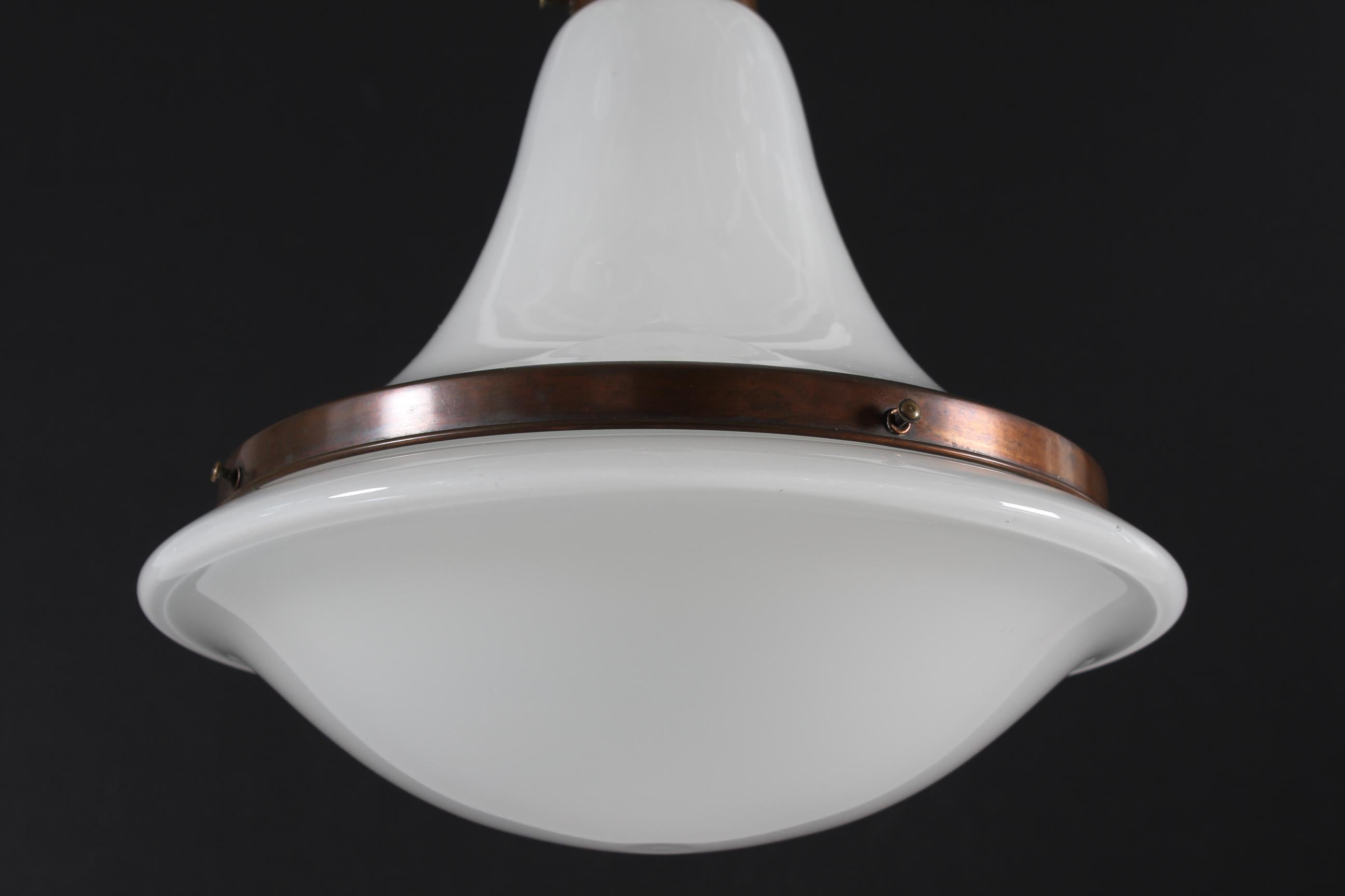 Gran lámpara colgante y de techo Bauhaus de cristal opalino con accesorios de cobre patinado de principios del siglo XX.
Al estilo del colgante Luzette diseñado por Peter Behrens en 1908 para Siemens-Schuckert.

Medidas:
Altura incl. tejadillo de