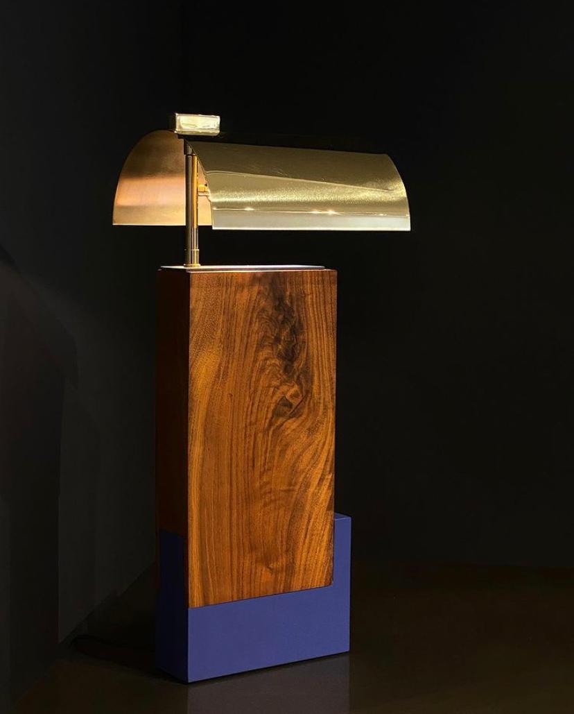 The 'Gemini' table lamp was inspired by simplicity of form, color scheme and respect of materials found in Bauhaus movement. It is shown above in a solid natural walnut, matte blue aluminum base and a solid brass arched shade. The polished brass is