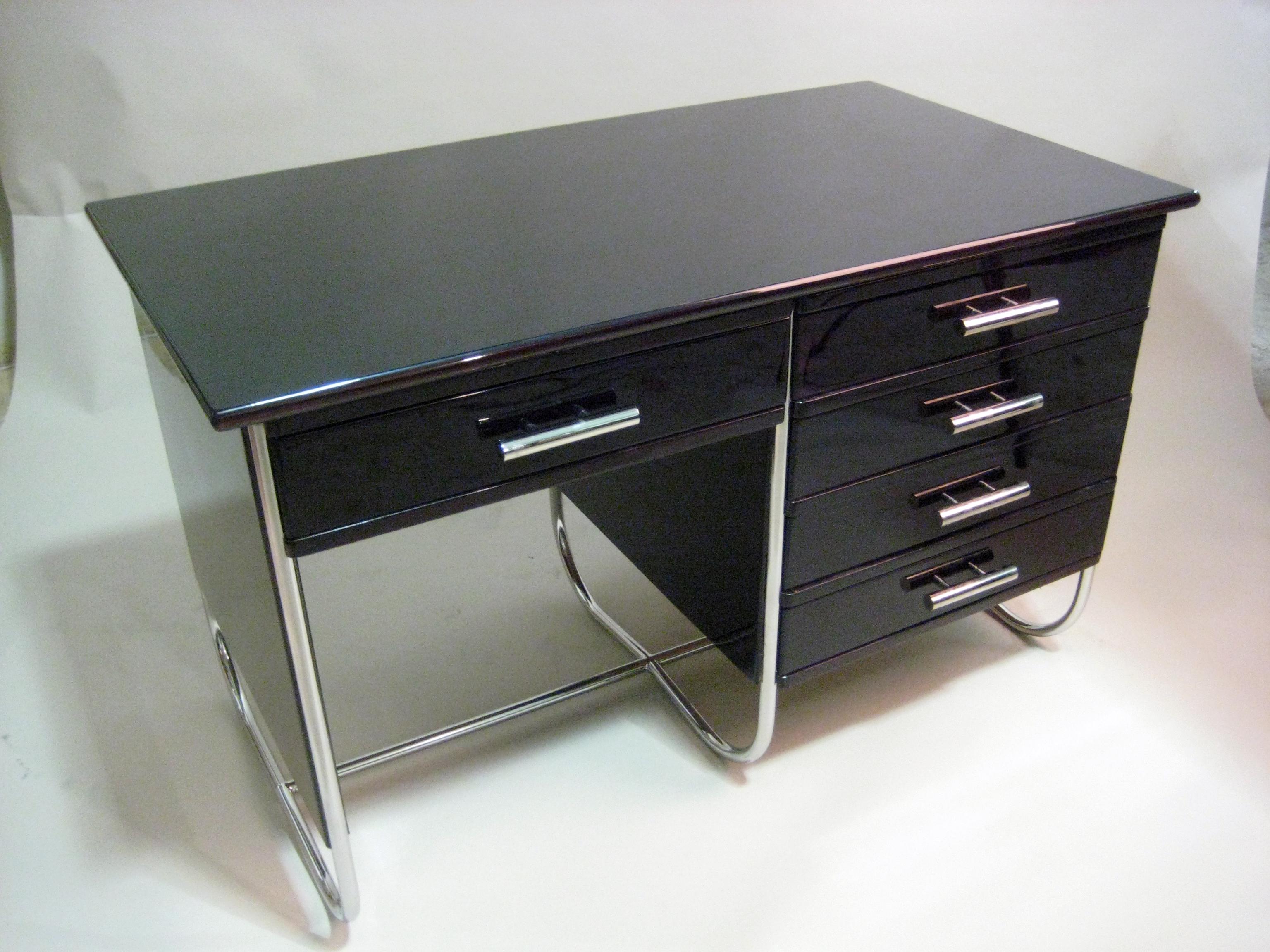 This sleek desk has all the influences of Breuer’s iconic S 285/2 Writing Desk; shiny tubular chrome frames the high-gloss wood storage elements. Whether used as a centerpiece in a home office or den, this modern desk’s compact size also makes it a