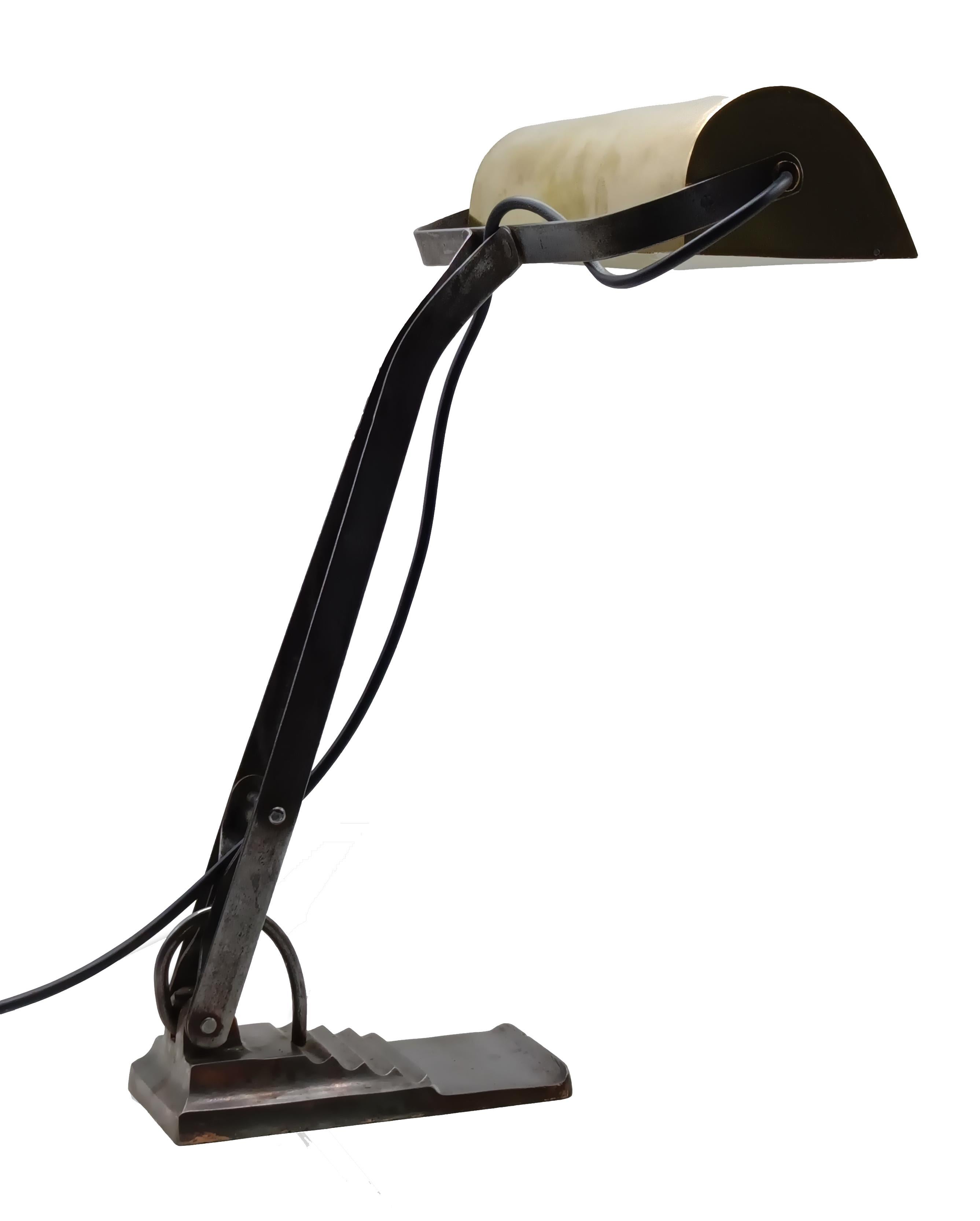 Característica lámpara de sobremesa de estilo Bauhaus, diseñada en 1940. La lámpara tiene una pesada base de hierro fundido y un casquillo metálico. La pesada base proporciona a la lámpara una posición sólida. Totalmente ajustable y con un aspecto