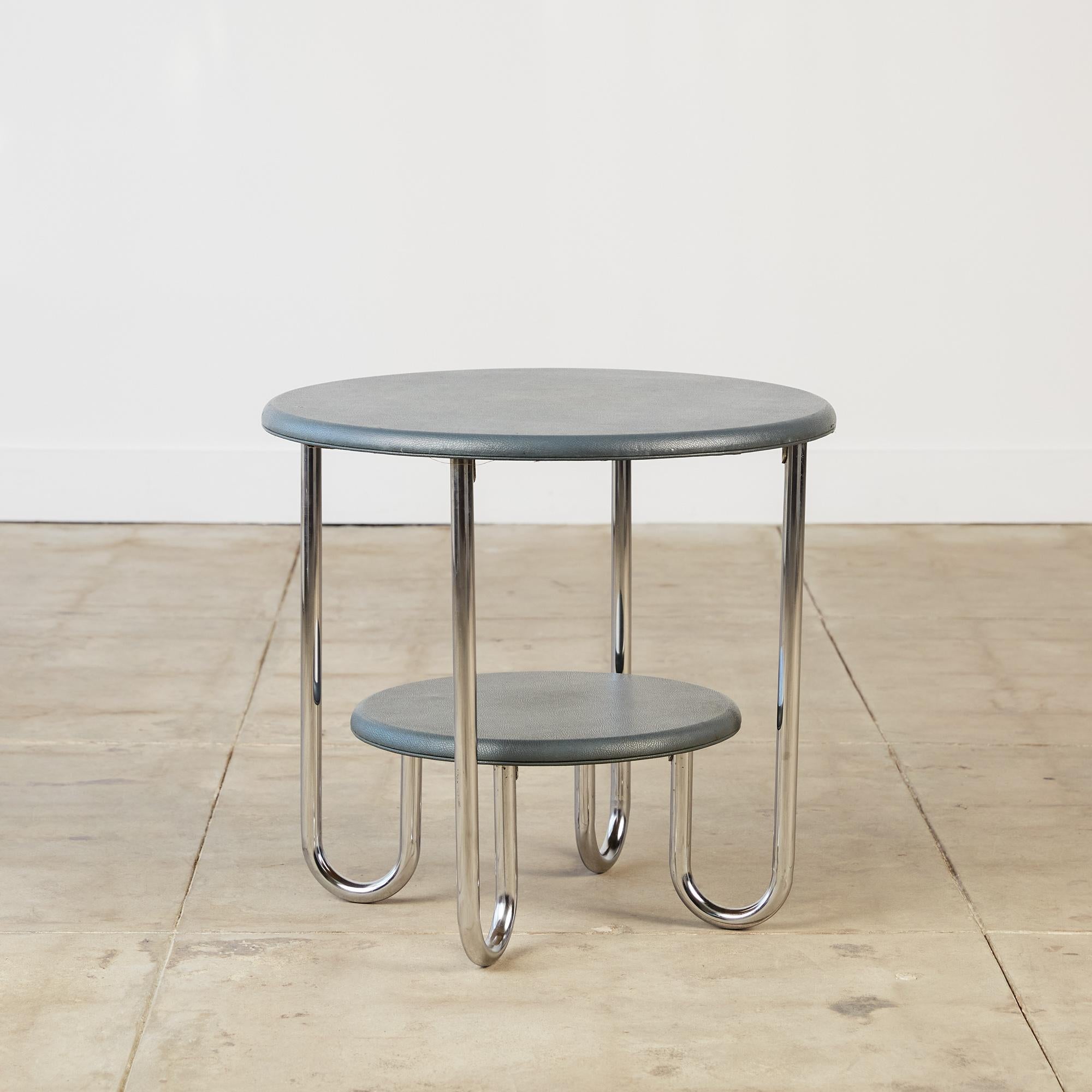 Two-tiered circular side table evocative of Bauhaus forms and elements. This piece is made of bent tubular steel frame with the tabletops covered in a gunmetal grey leatherette. The tubular steel connects the main surface to the smaller tier