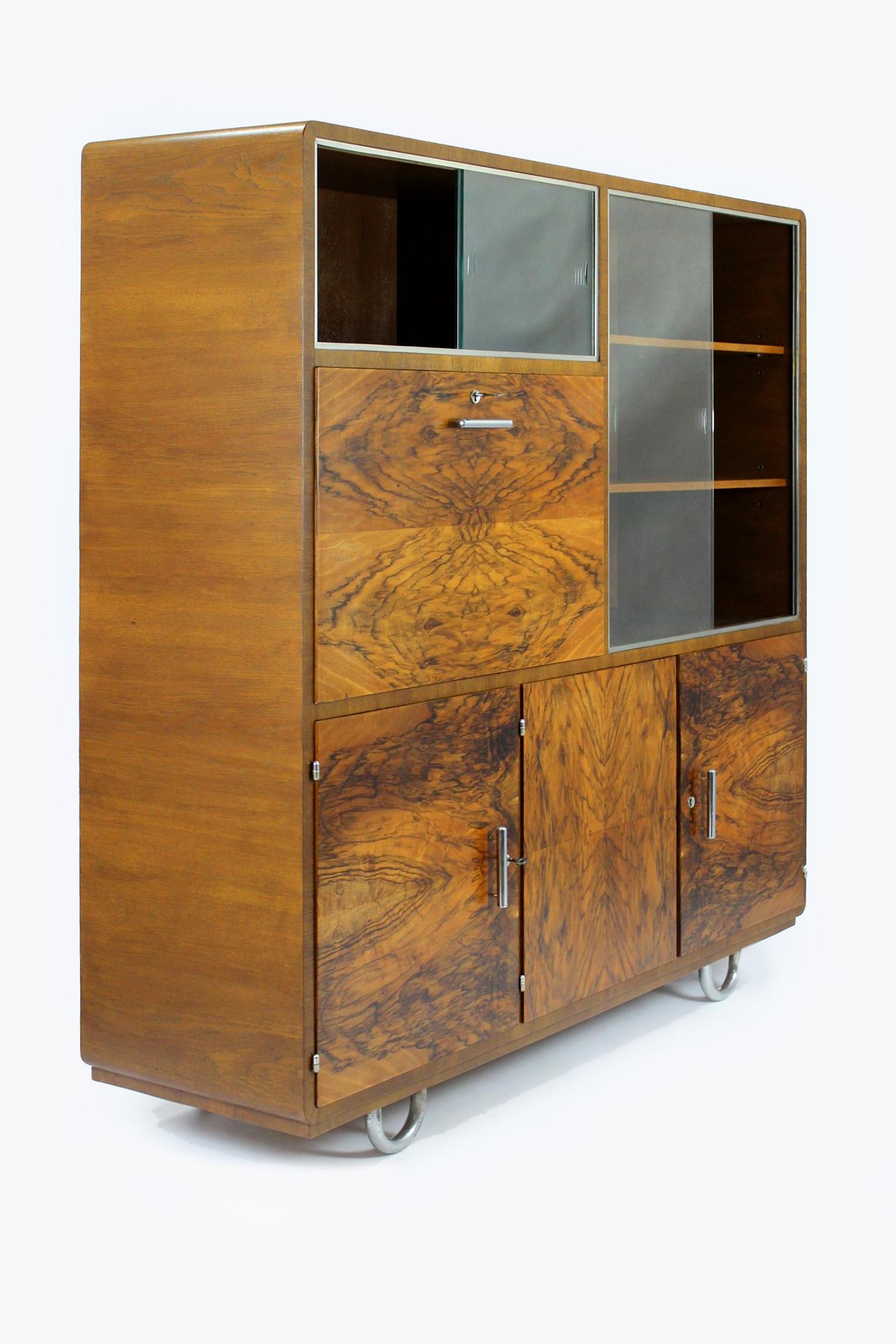 
Dieser Schrank im Bauhaus-Stil aus Eiche und Nussbaum wurde in den 1930er Jahren von Robert Slezak hergestellt. Der Schrank ist multifunktional und in 5 Teile unterteilt. Es gibt 4 Schubladen, 3 Regale, 2 Vitrinenteile mit Schiebeglas (das Glas ist