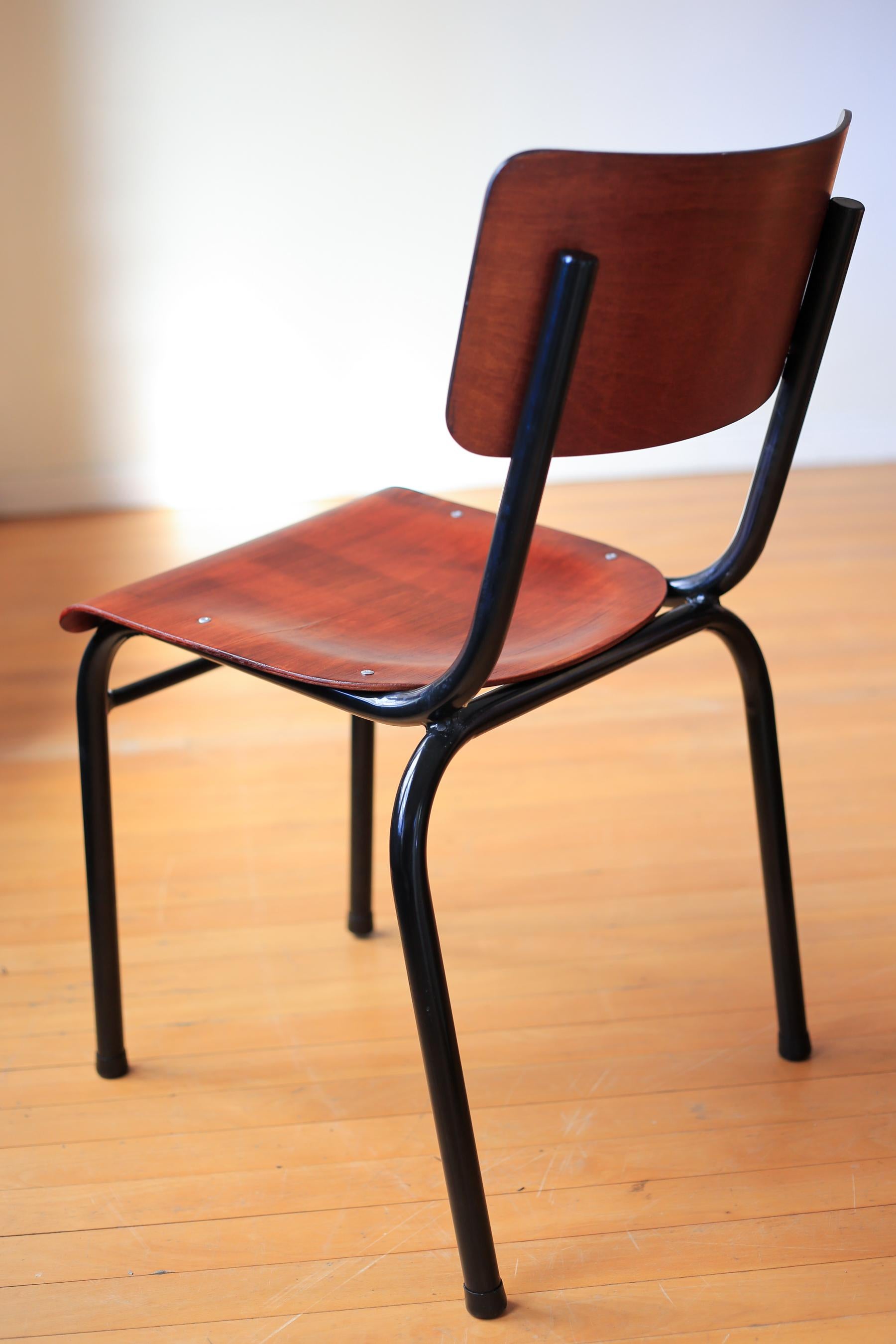 These refurbished chairs are 1940s school hall chair from South Africa. The frames have been sandblasted and powder coated to a glossy black and the molded plywood seats and backs have been stripped, sanded and spray coated. The seats and outside