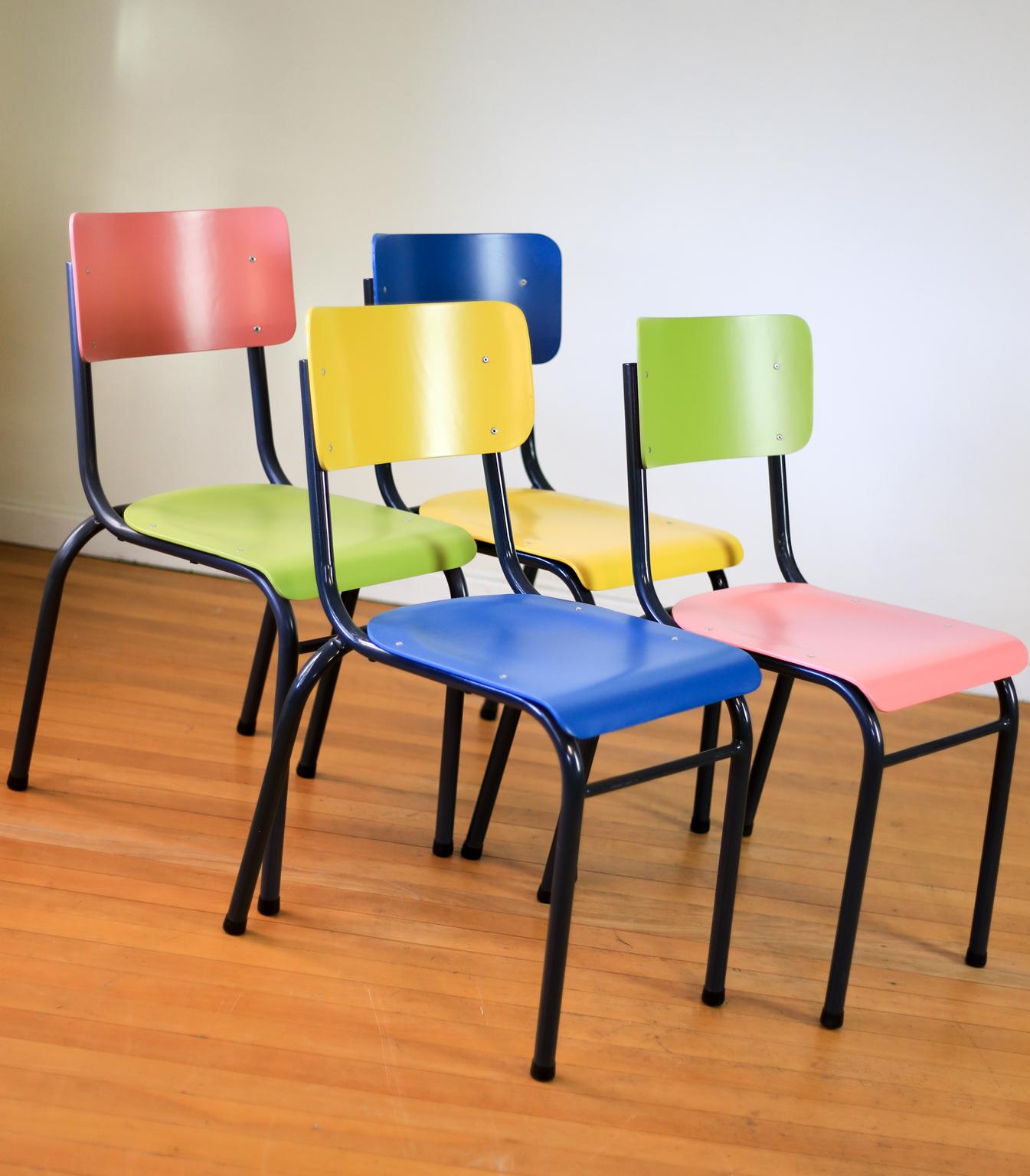A set of four brightly colored, refurbished 1940s school chairs from South Africa. Each chair has a different, two tone look. The frames have been sandblasted and powder coated dark grey and the molded plywood seats and backs have been stripped,