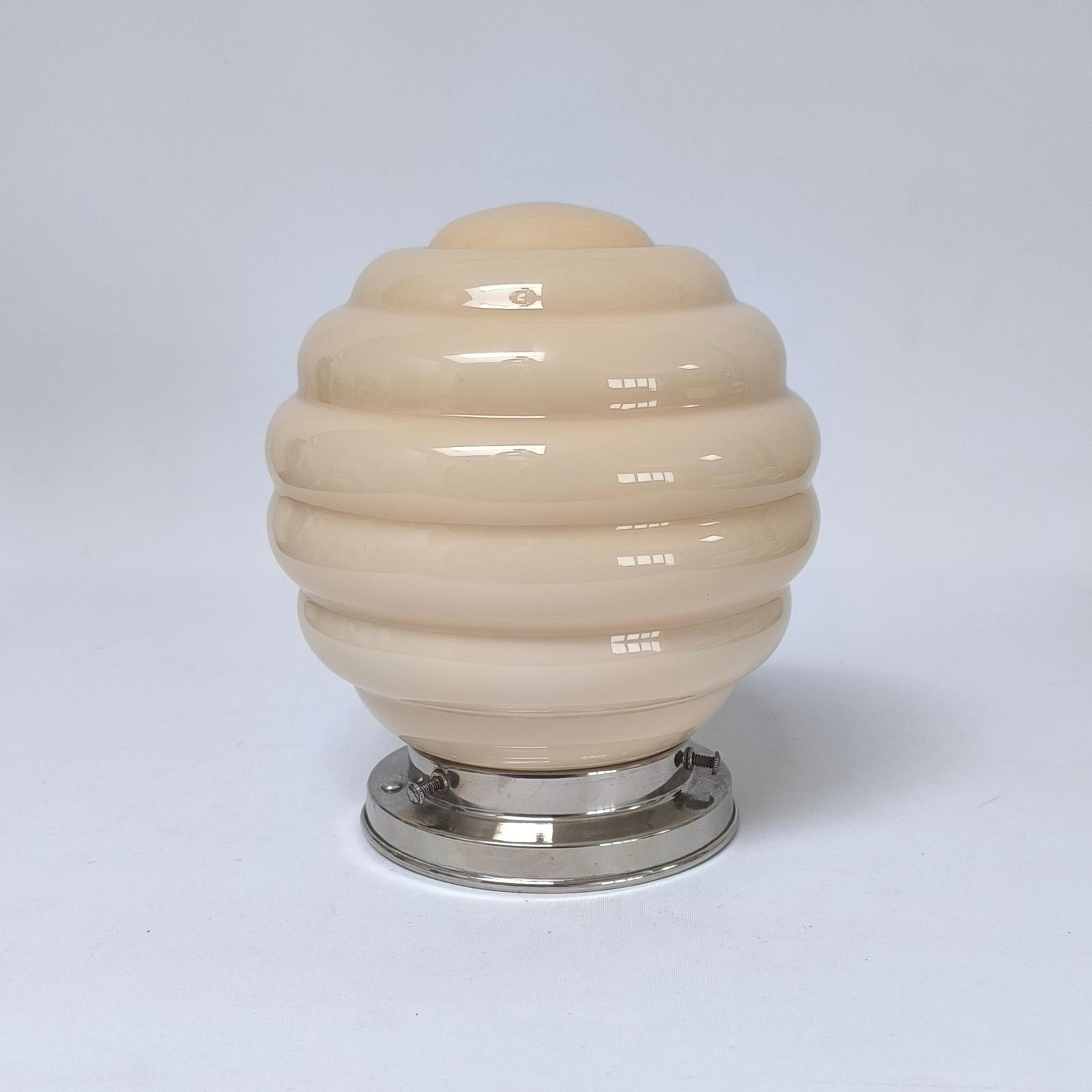 Round sconce with cased glass shade from the 1930s-40s, in Bauhaus / Art Deco style.

This is an elegant piece with a metal wall plate and a cased round shade made of two-layered glass, with an outer layer of butter yellow and white lining.

The