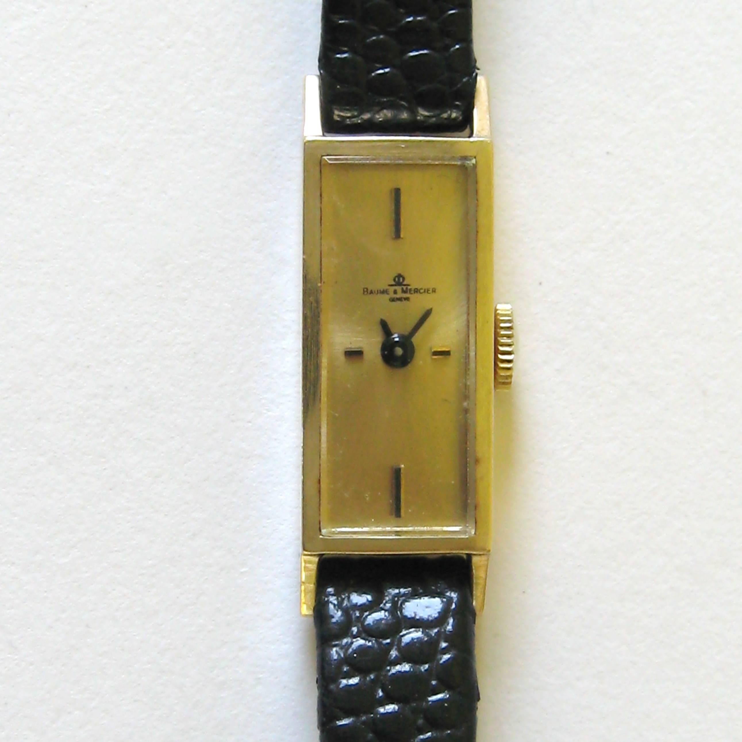 Classic 14k gold wristwatch from renowned watch company Baume & Mercier. Sleek, long rectangular face, four baton hour marks at 12, 3, 6 and 9 with a brushed gilt dial. 17 Jewel manual-wind movement, engraved inscription on the back, case number