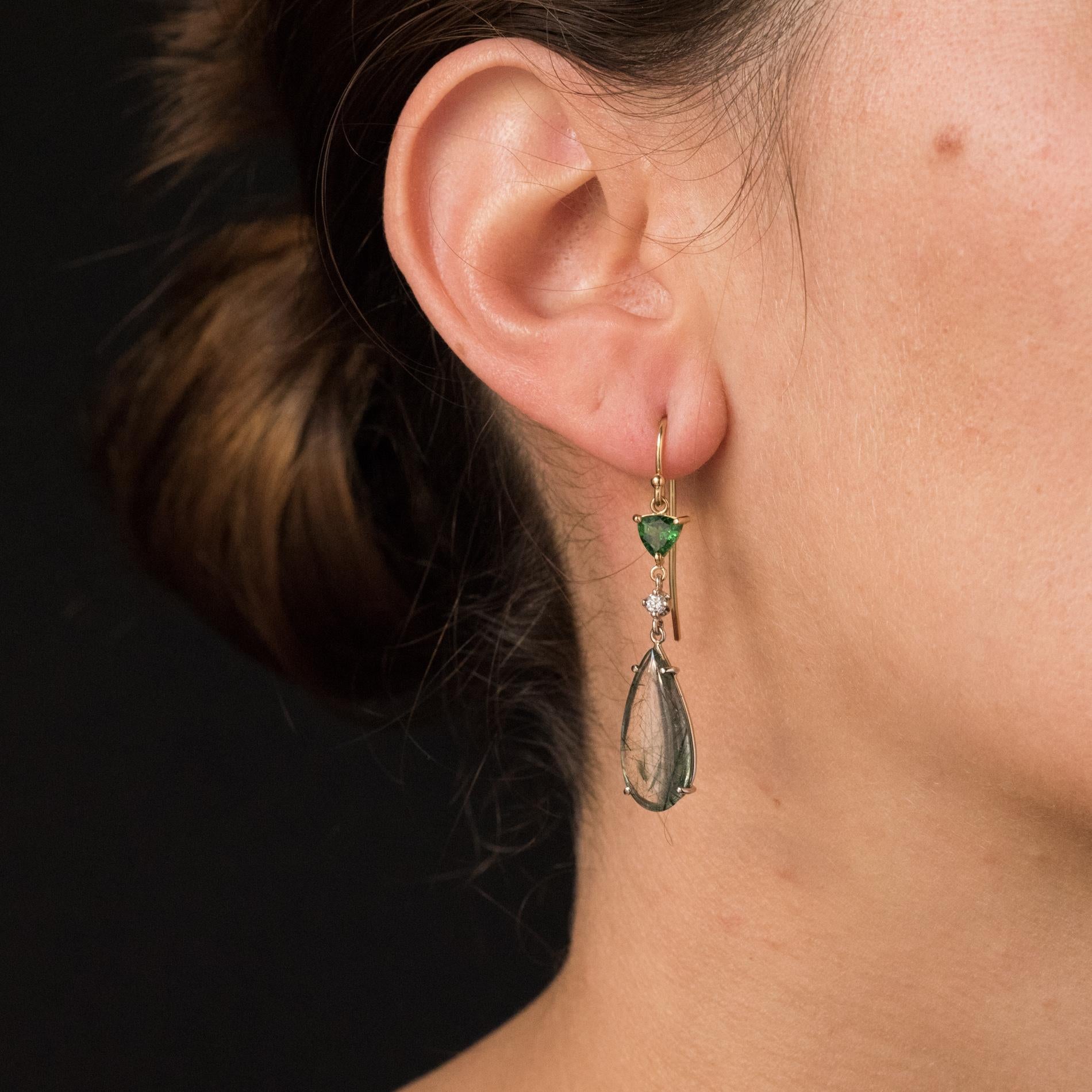 For pierced ears.
Baume's creation - Unique piece.
Pair of earrings in 18 karats yellow gold.
Each is adorned with a troidy green garnet that holds a brilliant-cut diamond and at the base a drop of quartz with ruched cabochon, all set with claws.