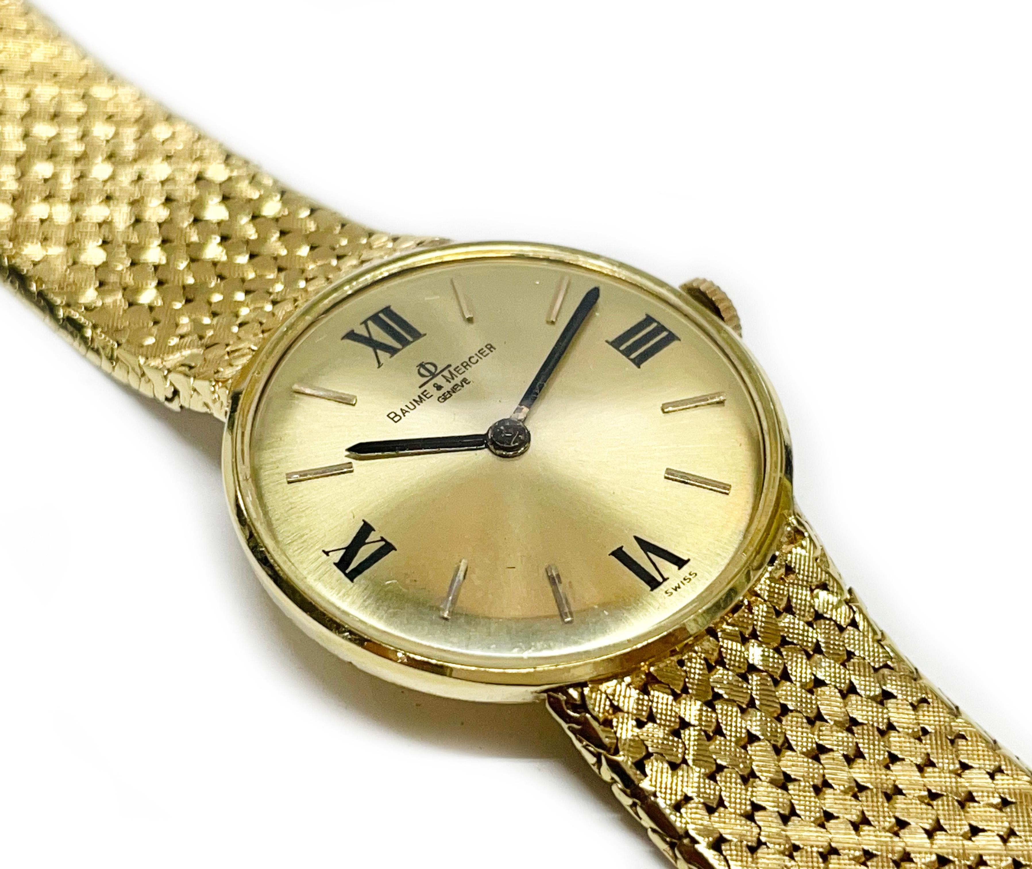 14 Karat Baume et Mercier Gelbgold-Armbanduhr. Die Uhr verfügt über ein rundes goldenes Zifferblatt, römische Zahlen bei zwölf, drei, sechs und neun. Die Uhr verfügt über Stunden- und Minutenzeiger im Stil eines Stabes. Das Armband ist aus Mesh mit