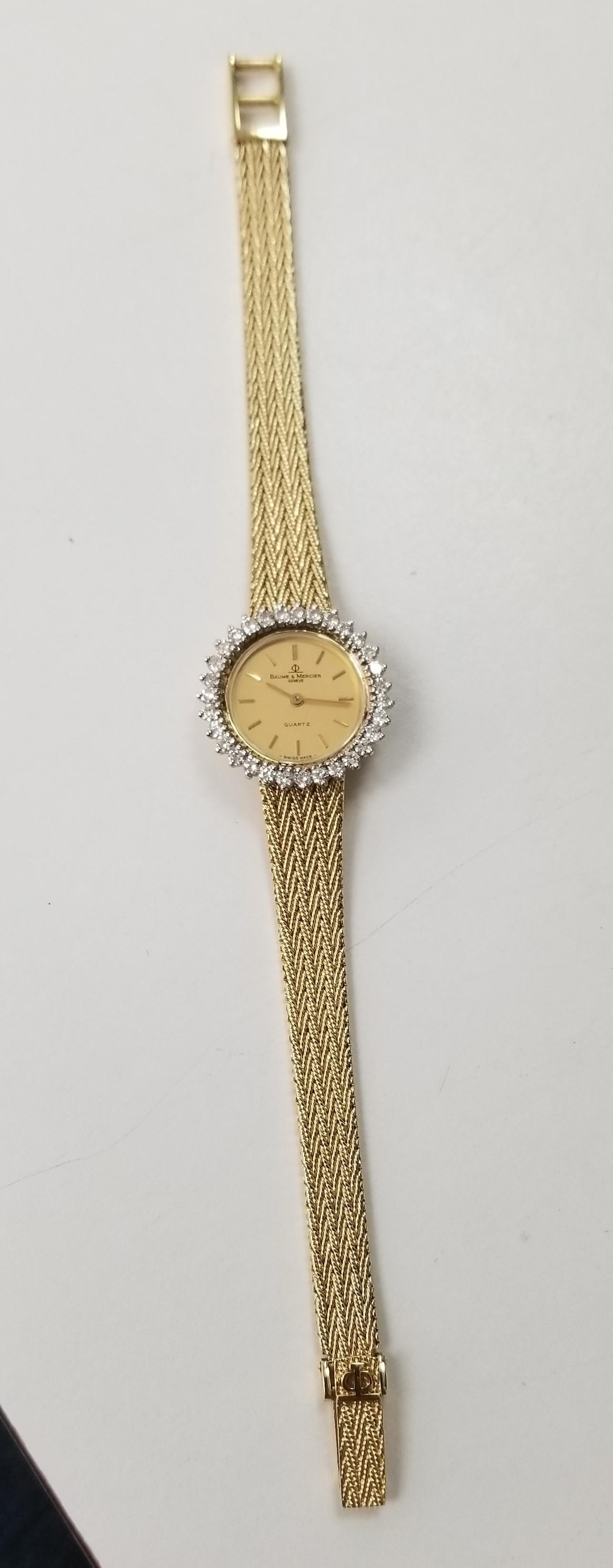 Baume & Mercier 14k yellow gold woven mesh band and diamond watch, containing 31 full cut diamonds of very fine quality weighing 1.00cts.  The watch is in very good condition and measures 6 9/16 or 6 13/16 inches.  the watch has a cabochon sapphire.