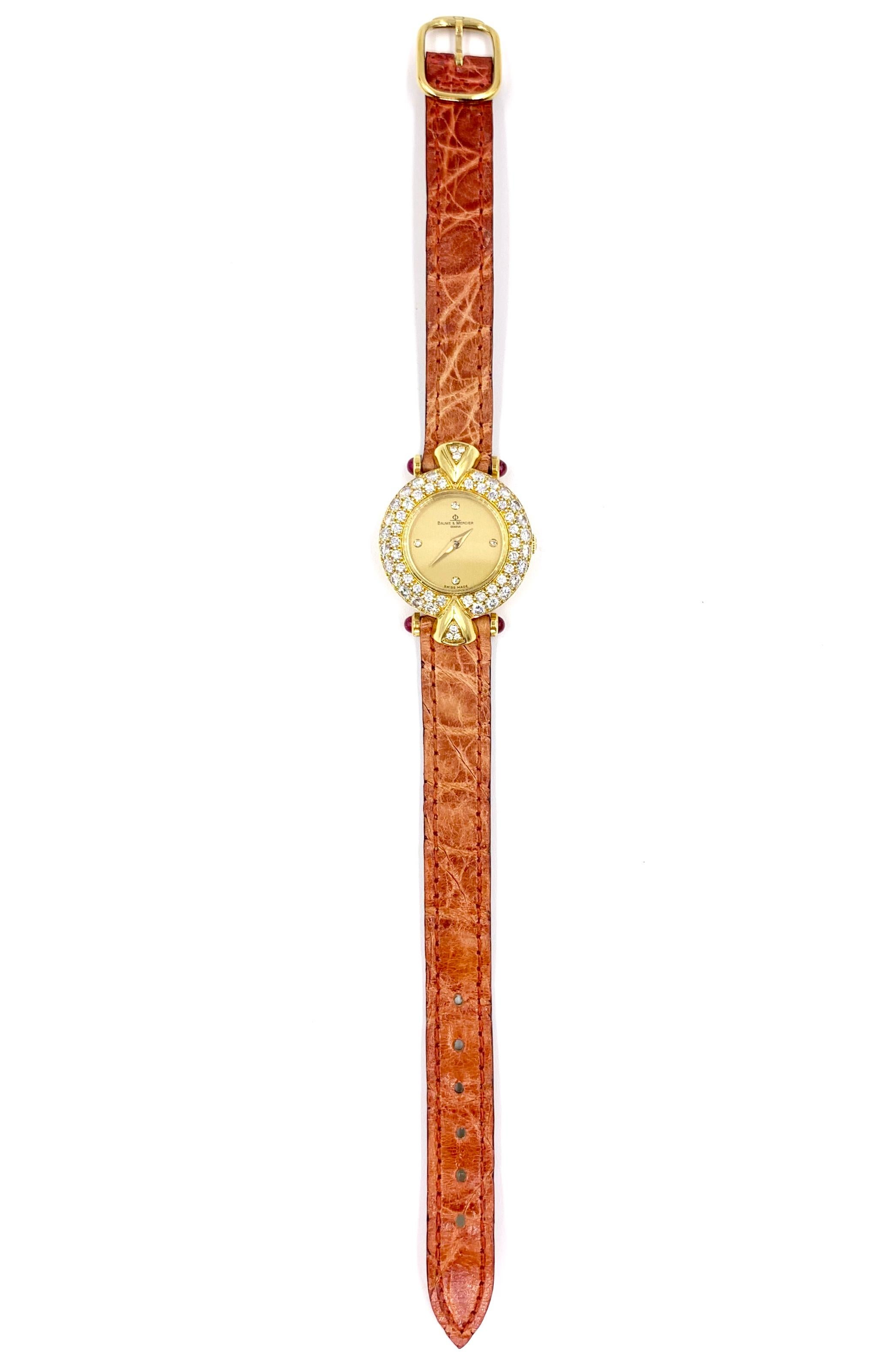 A simply beautiful and timeless 18 karat yellow gold 22mm Baume and Mercier ladies quartz watch with a champagne dial and pave diamond encrusted case and cabochon ruby lugs on a burnt orange leather strap. Dial features bezel set diamonds at the 12,