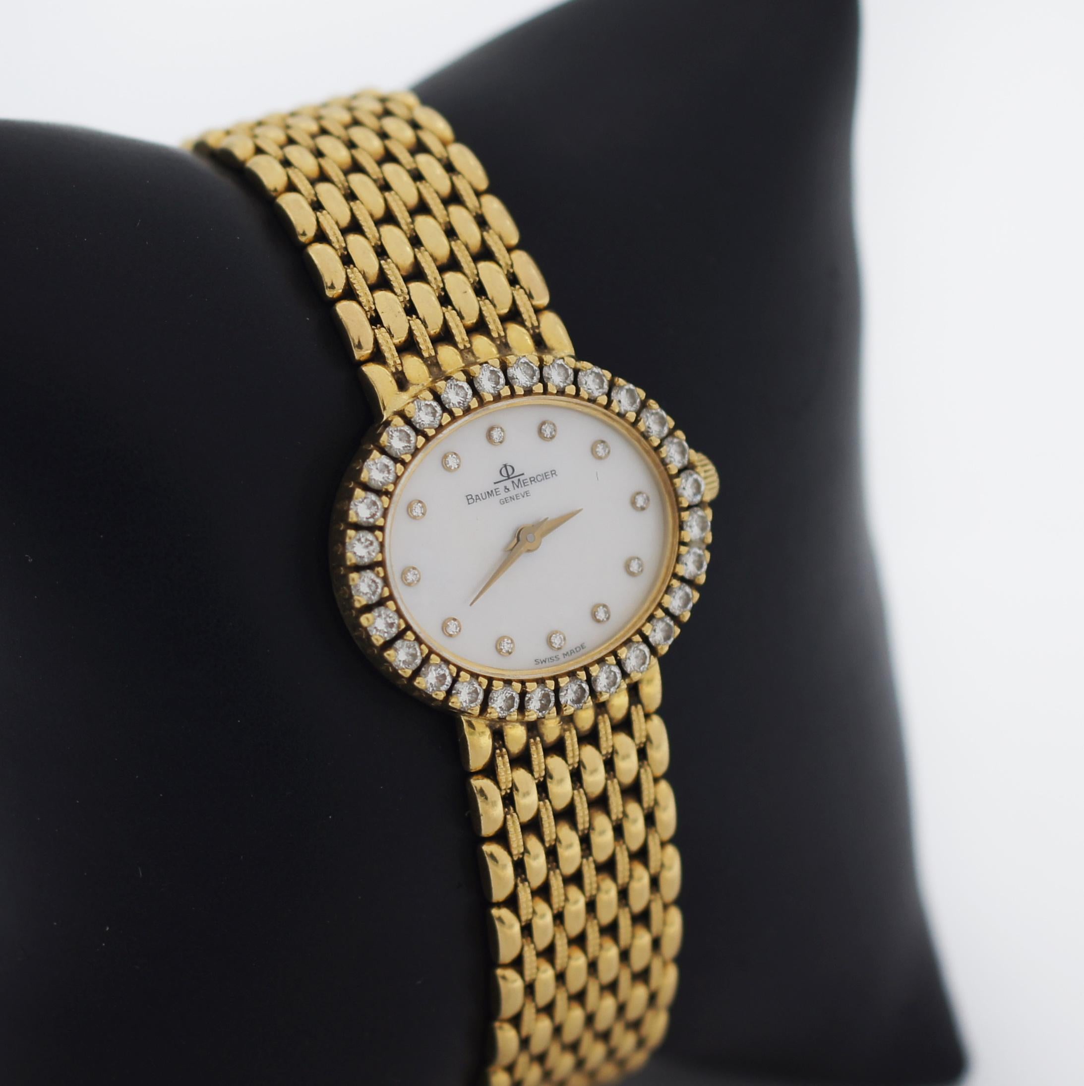 Baume & Mercier
Model Number: 18310 9
18k Yellow Gold Case and Bracelet
28 Natural Diamond Bezel 
Approx. Total Carats: 1.12ctw
Round Brilliant Cut
Color: G - H
Clarity: VS1 - VS2
Mother of Pearl Dial with Gold hands and 12 Diamonds