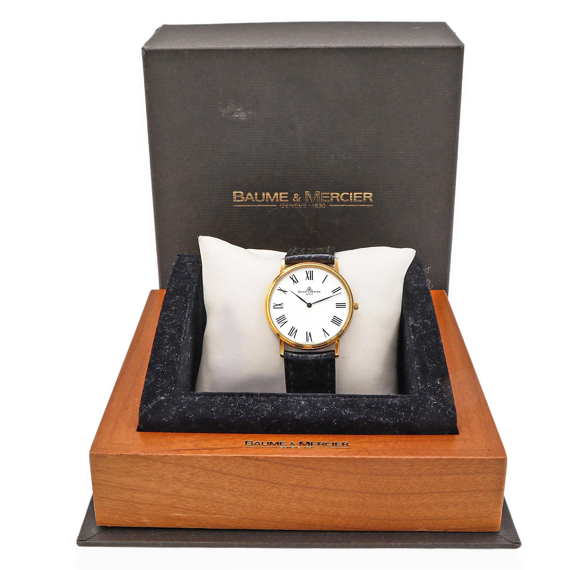 This elegant Baume & Mercier timepiece exudes timeless sophistication with its 18K yellow gold case, radiating warmth and luxury. The crisp white dial is adorned with classic Roman numeral markers, offering a refined and traditional aesthetic.