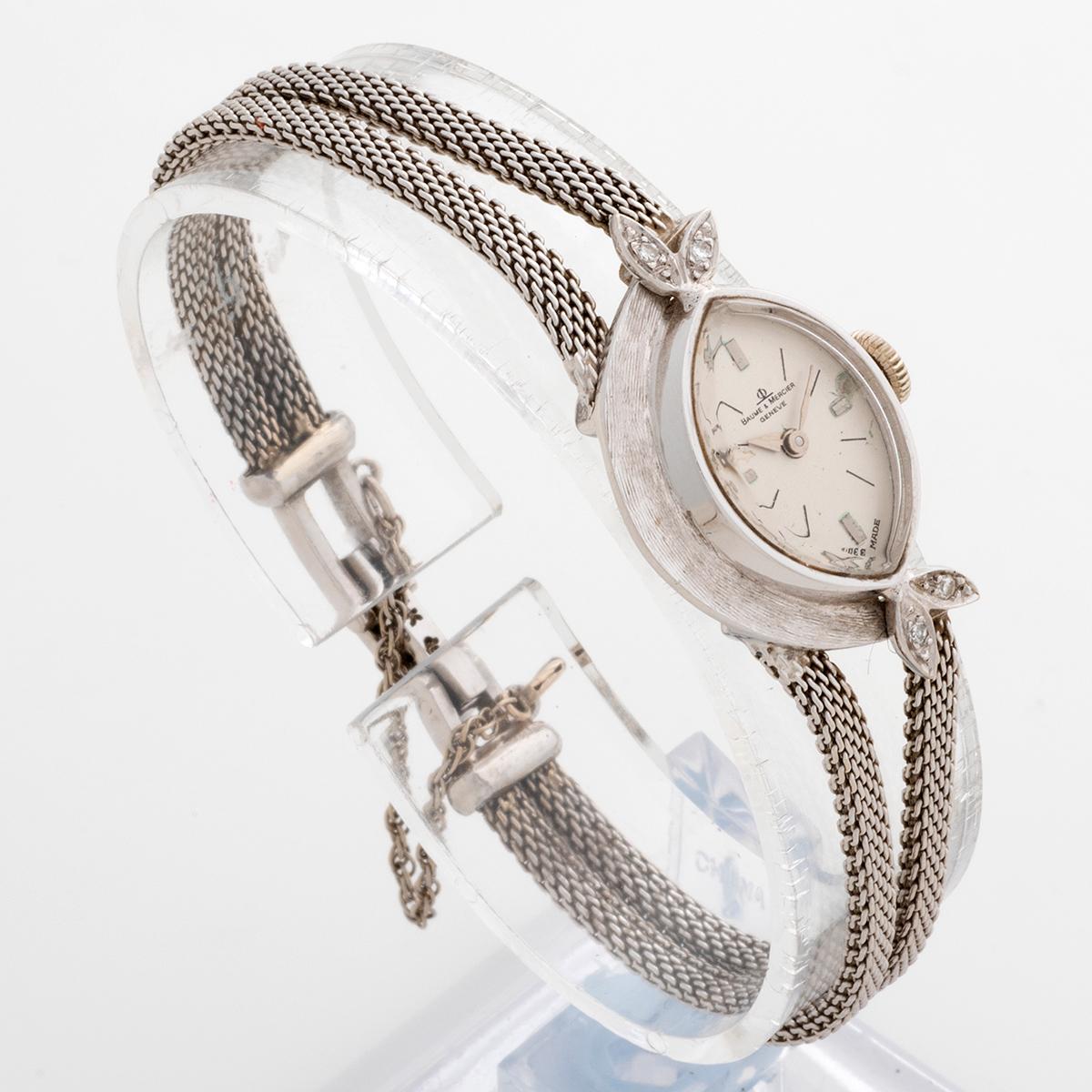 Our very rare vintage Baume & Mercier manually wound cocktail watch features an elliptical white gold case stamped 14k with 4 diamonds set to the lugs, and two strand rope bracelet in 14k white gold, fastened by a flip clasp with safety chain, also