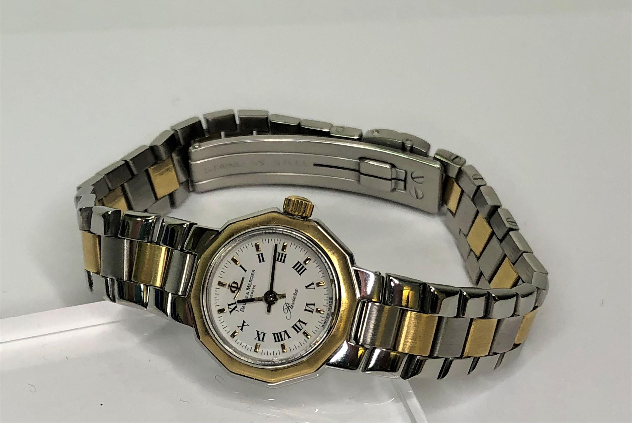 Baume & Mercier Geneve Riviera watch.
Two tone watch with 18 karat yellow gold and sterling silver.
White face with Roman numeral hour marks.
Band graduates from approximately 12mm near face to 10mm near clasp.  
Face is approximately 20mm wide