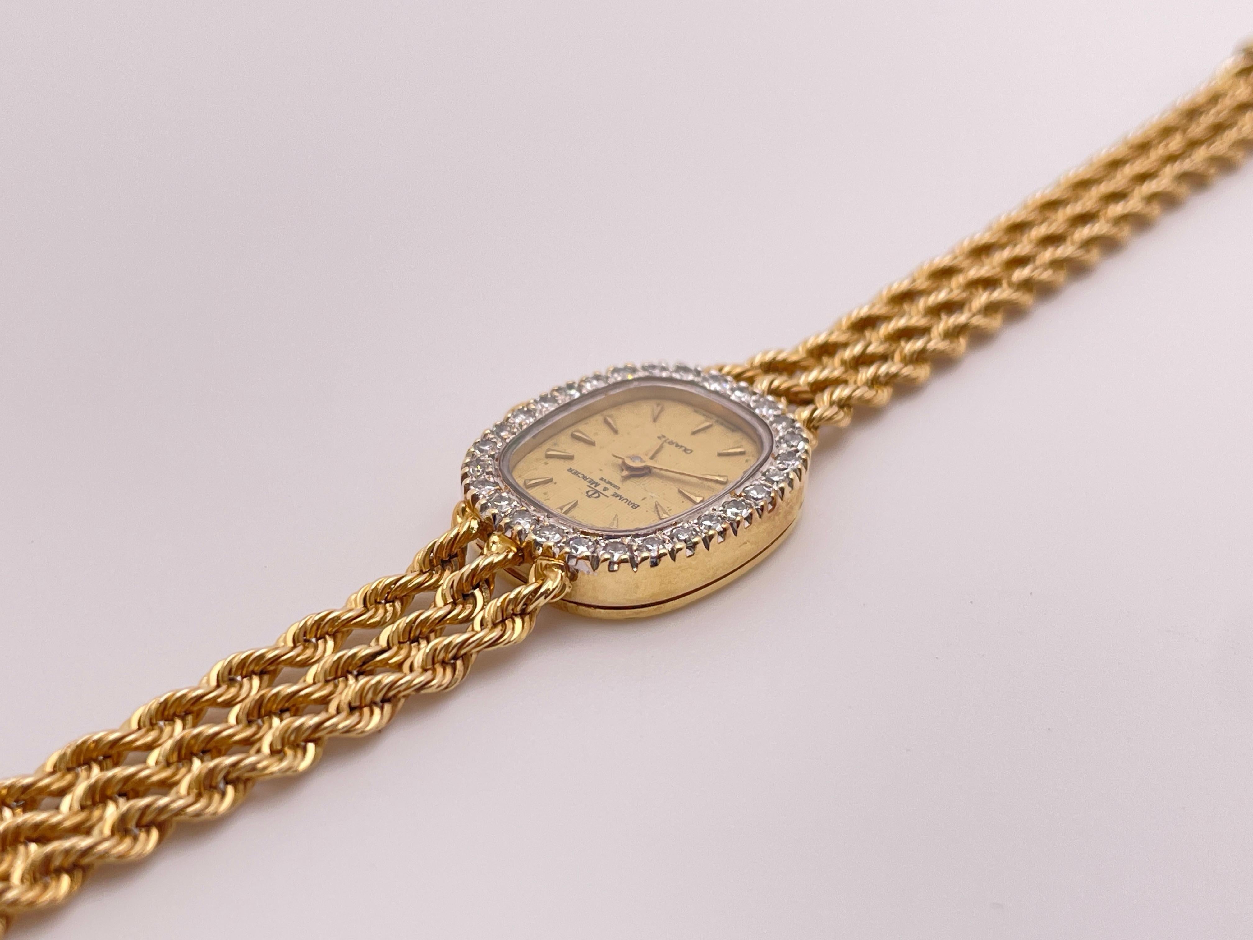 An original 14K yellow gold Diamond Baume & Mercier womens watch. Designed with a triple gold rope bracelet, an oval face, a magnificent diamond bezel, sapphire crown, and original Baume and Mercer buckle. Mounted with 28 round brilliant cut natural