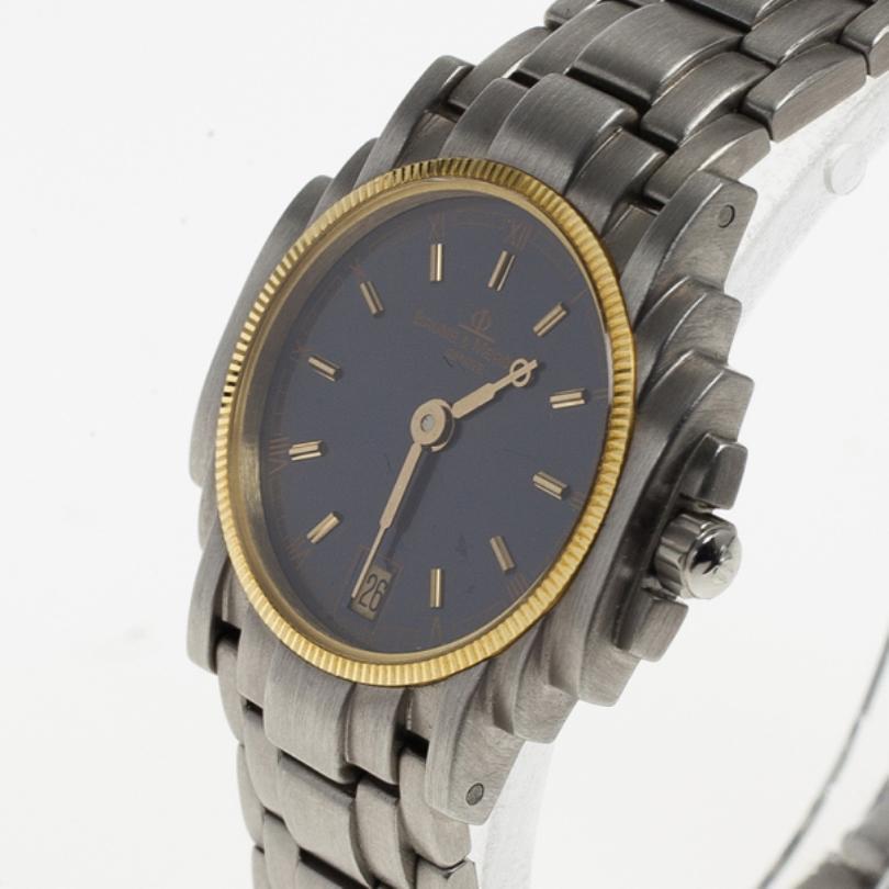 Get noticed as you flaunt this Baume & Mercier accessory. Crafted from stainless steel, this watch features a blue dial with gold Roman numerals and index bars, hands and a date window. This timepiece showcases a bezel in gold highlighting the dial.