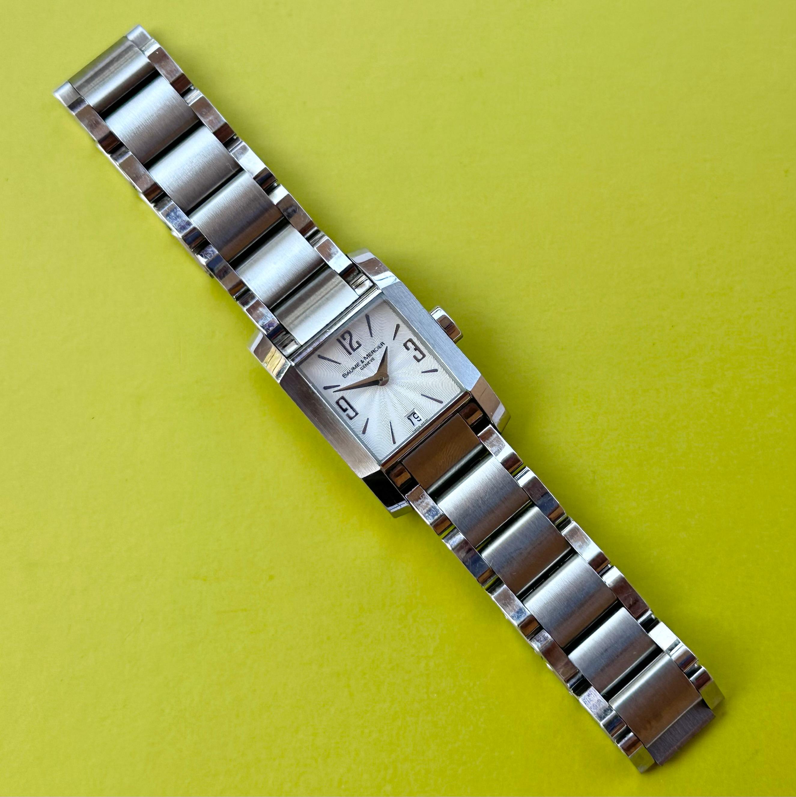Brand: Baume & Mercier

Model: Hampton

Reference Number: 65488

Country Of Manufacture: Switzerland

Movement: Quartz

Case Material: Stainless steel

Measurements : Case width: 22 x 34 mm. (without crown)

Band Type : Stainless steel

Band