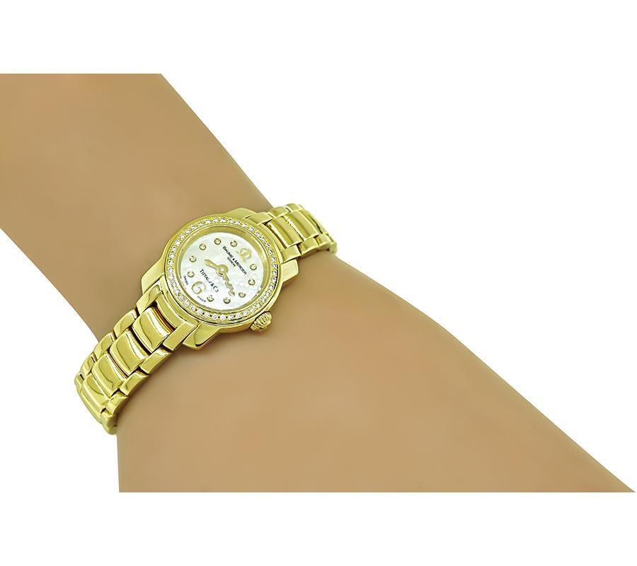 This is a gorgeous diamond 18k yellow gold lady's watch by Baume & Mercier and Tiffany & Co. The watch features sparkling round cut diamond accents. The mother of pearl dial is signed Baume & Mercier Geneve Tiffany & Co. The watch has a serial
