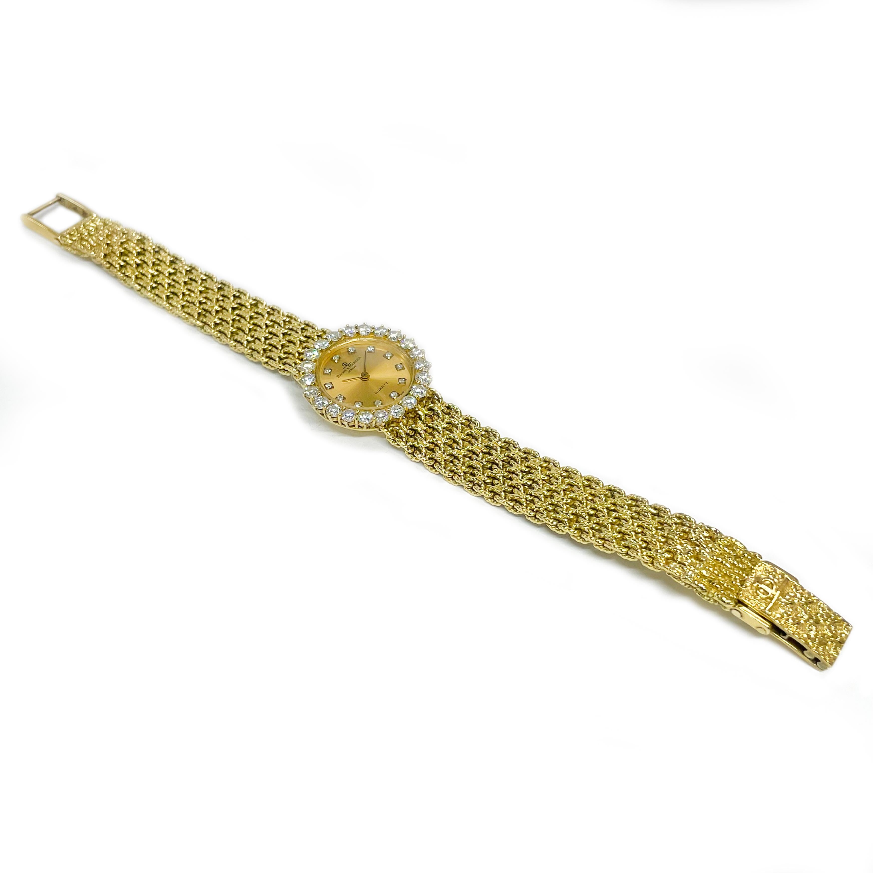 Baume & Mercier 18 Karat Yellow Gold Diamond Quartz movement Wristwatch. The watch features a round gold dial with hour and minute hands and round diamonds set at each hour. Set around the bezel are twenty-two 3mm brilliant-cut round diamonds. The