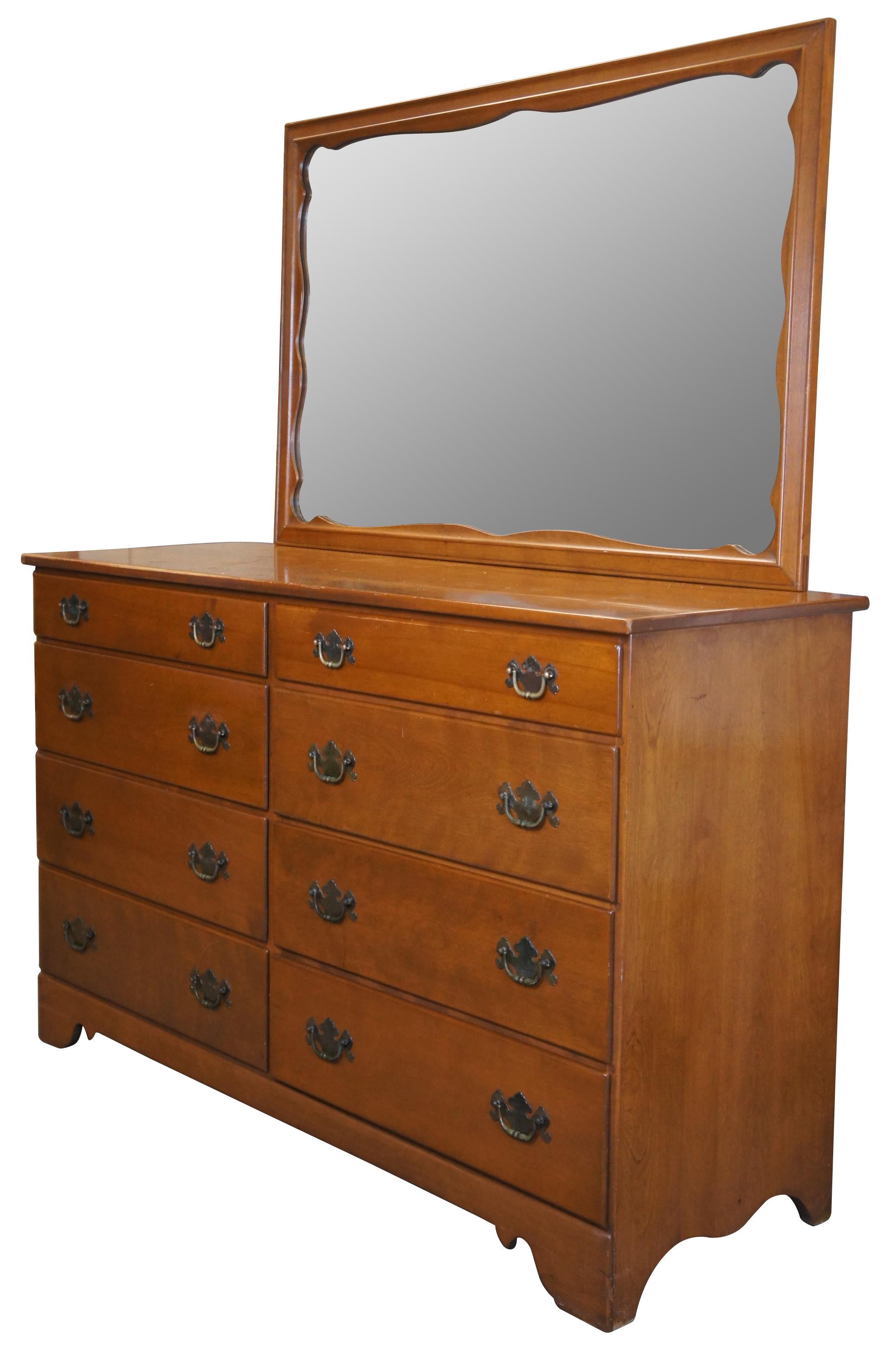 Vintage Ethan Allen Baumritter Heirloom Nutmeg dresser with looking glass. Made of maple featuring rectangular form with serpentine skirt, large mirror and eight drawers with colonial brass pulls.

Measures: 19.5