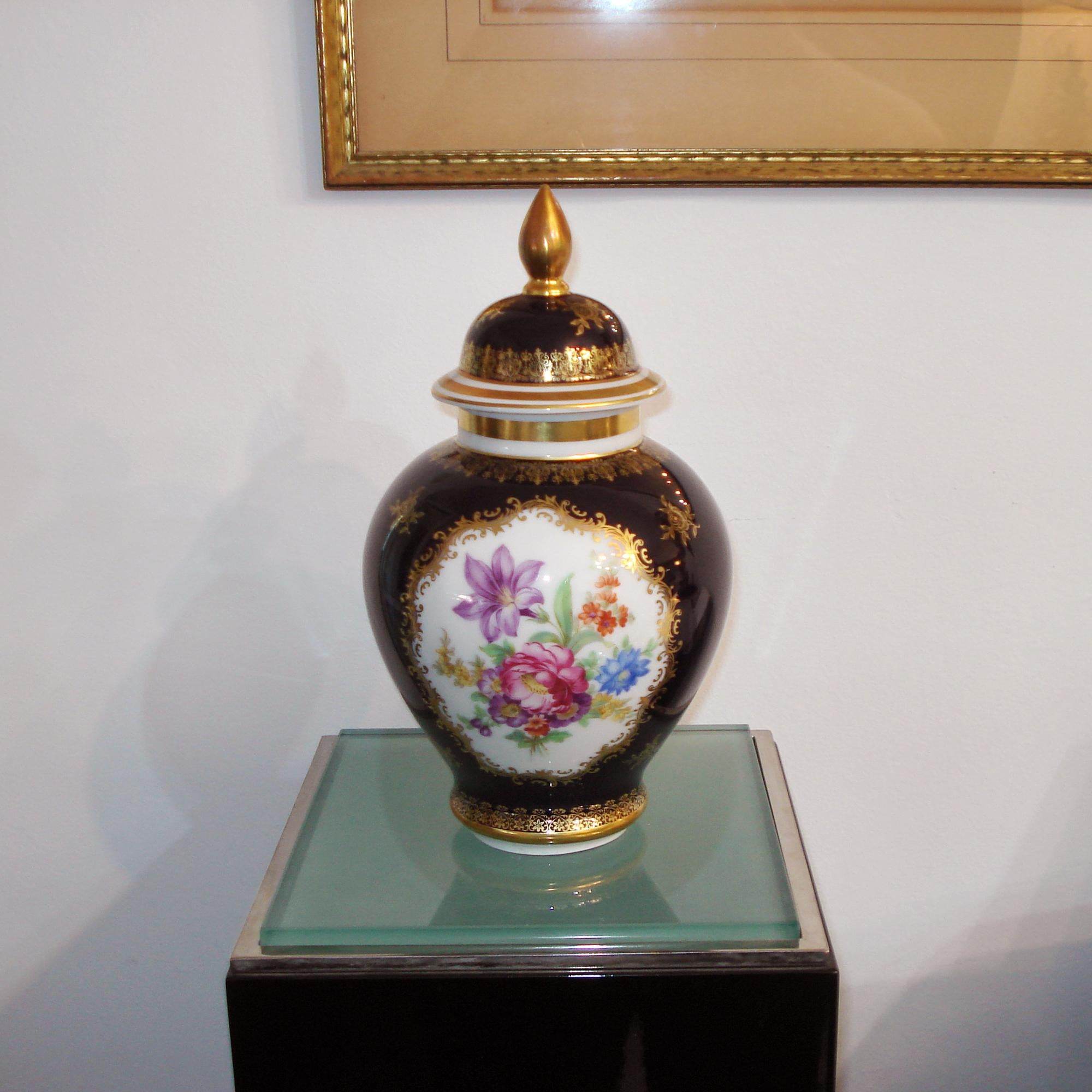 Porzellanurne mit Deckel, kobaltblau mit zwei handgemalten Medaillons mit Blumendekor, reich verziert mit 24K Goldmalerei. Hergestellt von Bavaria Schumann Arzberg, Deutschland 1960er Jahre. Markiert auf der Unterseite.
Abmessungen:
 Gesamthöhe,