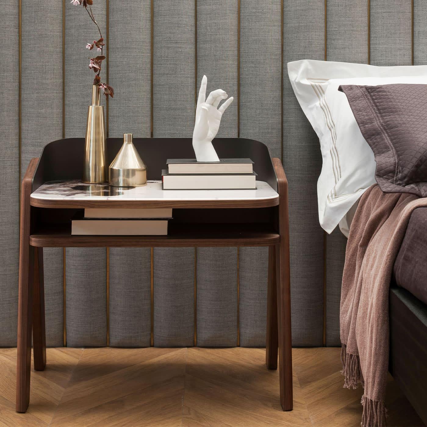 Dynamic lines trace the profiles of this exclusive nightstand, immediately capturing the eye with the fine print of Trinity White marble that adorns its glass top's back. Marked by a daring upside-down V shape, the solid walnut legs encounter an