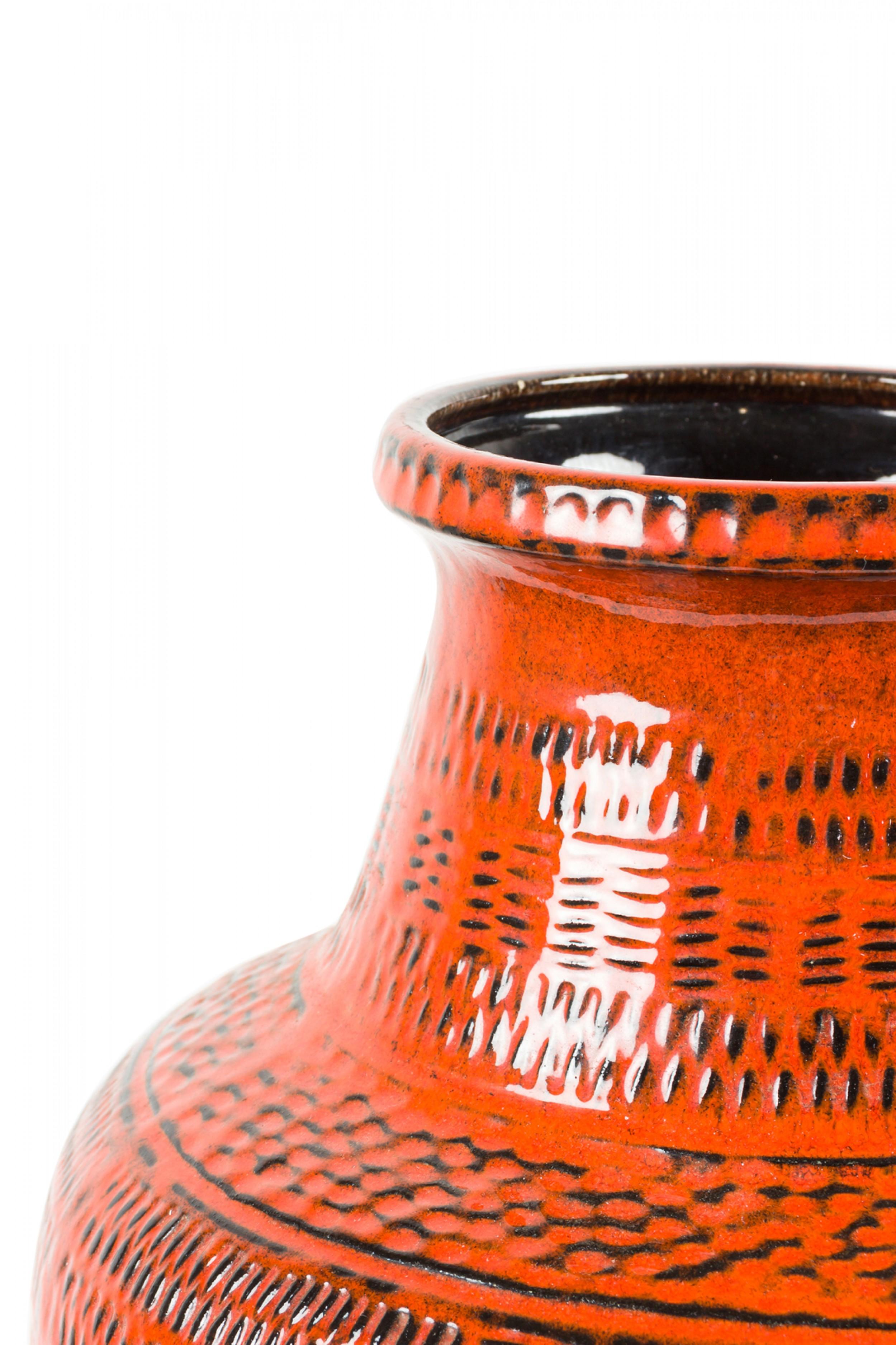 West German mid-century cylindrical ceramic vase with a raised irregular pattern of geometric shapes, highlighted and dotted in black against a rust orange glaze. (BAY KERAMIC 
