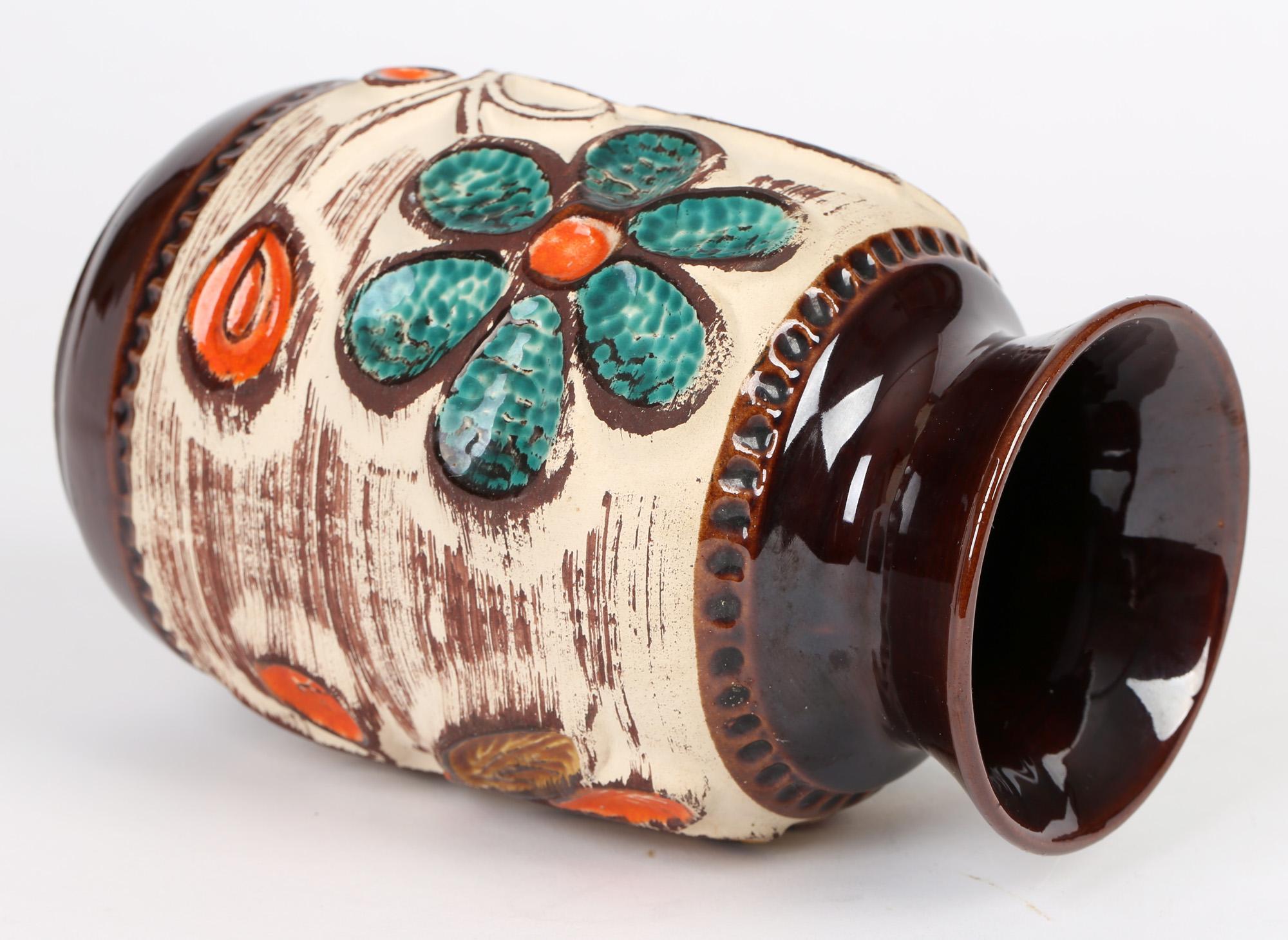 Un elegante vaso in ceramica d'arte della Germania occidentale della metà del secolo scorso con disegni floreali in rilievo di Bay Keramik. Il vaso poggia su uno stretto piede arrotondato non smaltato con una base incassata e il corpo di forma