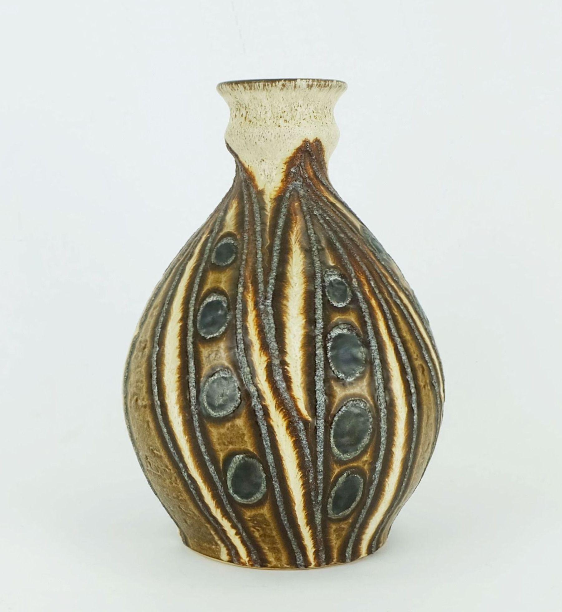Un fantastique vase vintage d'Allemagne de l'Ouest fabriqué par Bay Keramik dans les années 1970. Modèle 610 25 avec glaçure mate beige et brune combinée à des motifs de vagues et de cercles en glaçure lave brillante.
 
Hauteur 10