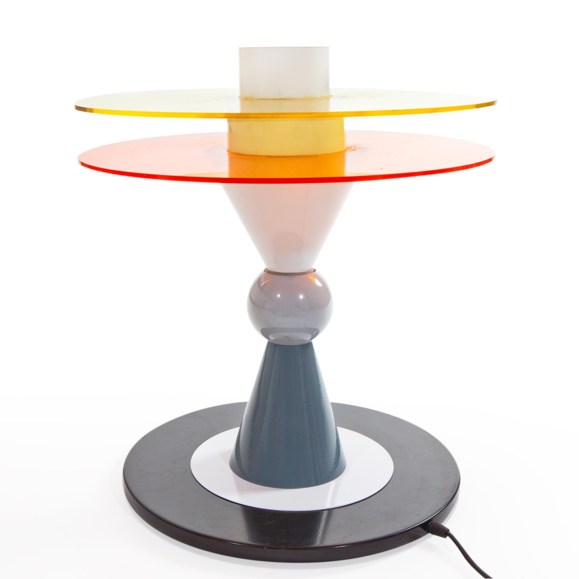 Hier sehen Sie die US-amerikanische verkabelte Bay Table Lamp aus Glas, Aluminium und Plexiglas, die 1983 von Ettore Sottsass für Memphis Milano entworfen wurde.

Ettore Sottsass wurde 1917 in Innsbruck geboren. Im Jahr 1939 schloss er sein