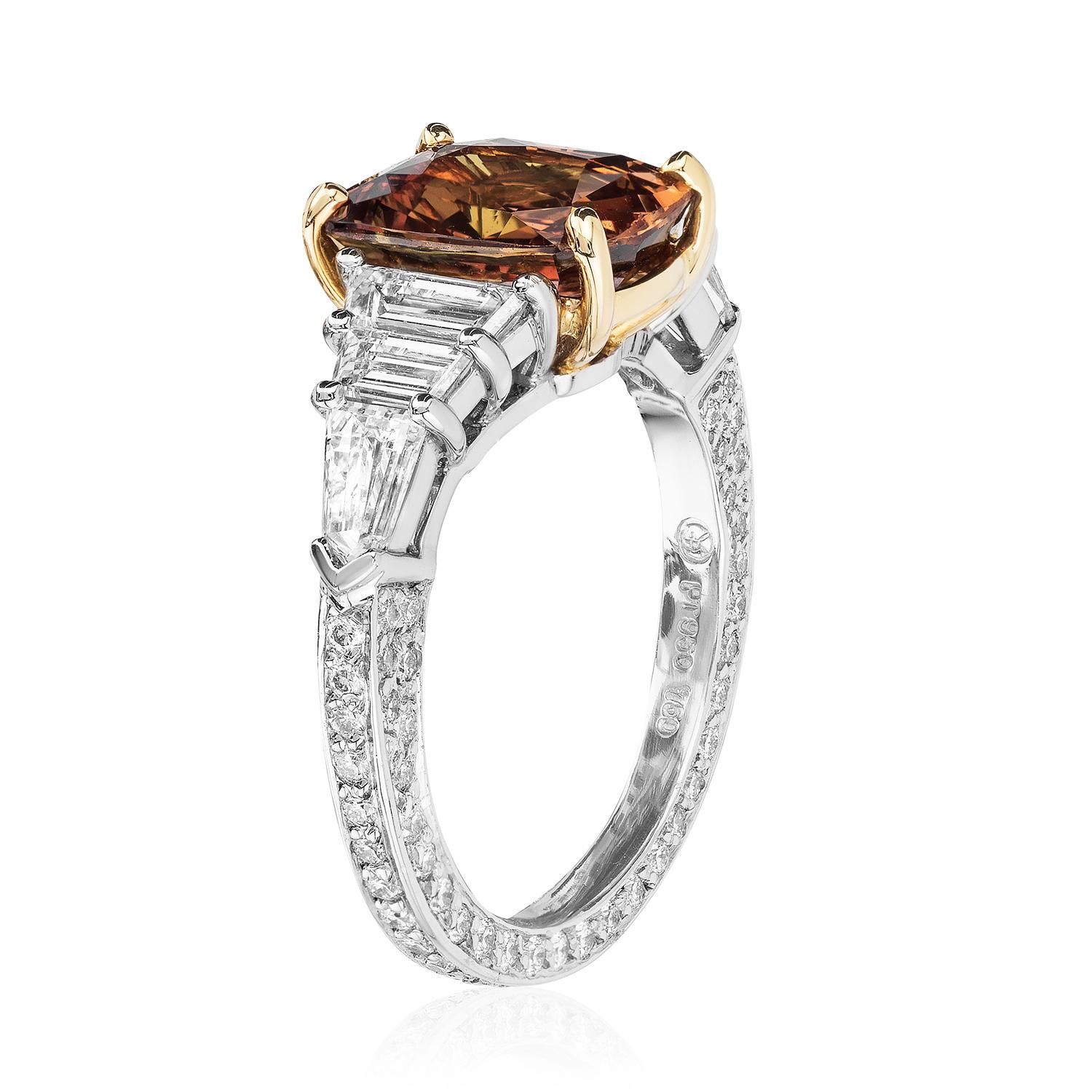 A platinum & 18kt yellow gold ring centered upon a rare 3.82 carat natural unheated cushion orange sapphire, certified by C. Dunaigre Consulting, flanked by two trapezoid colorless diamonds and a bullet colorless diamond on each side with micropavé