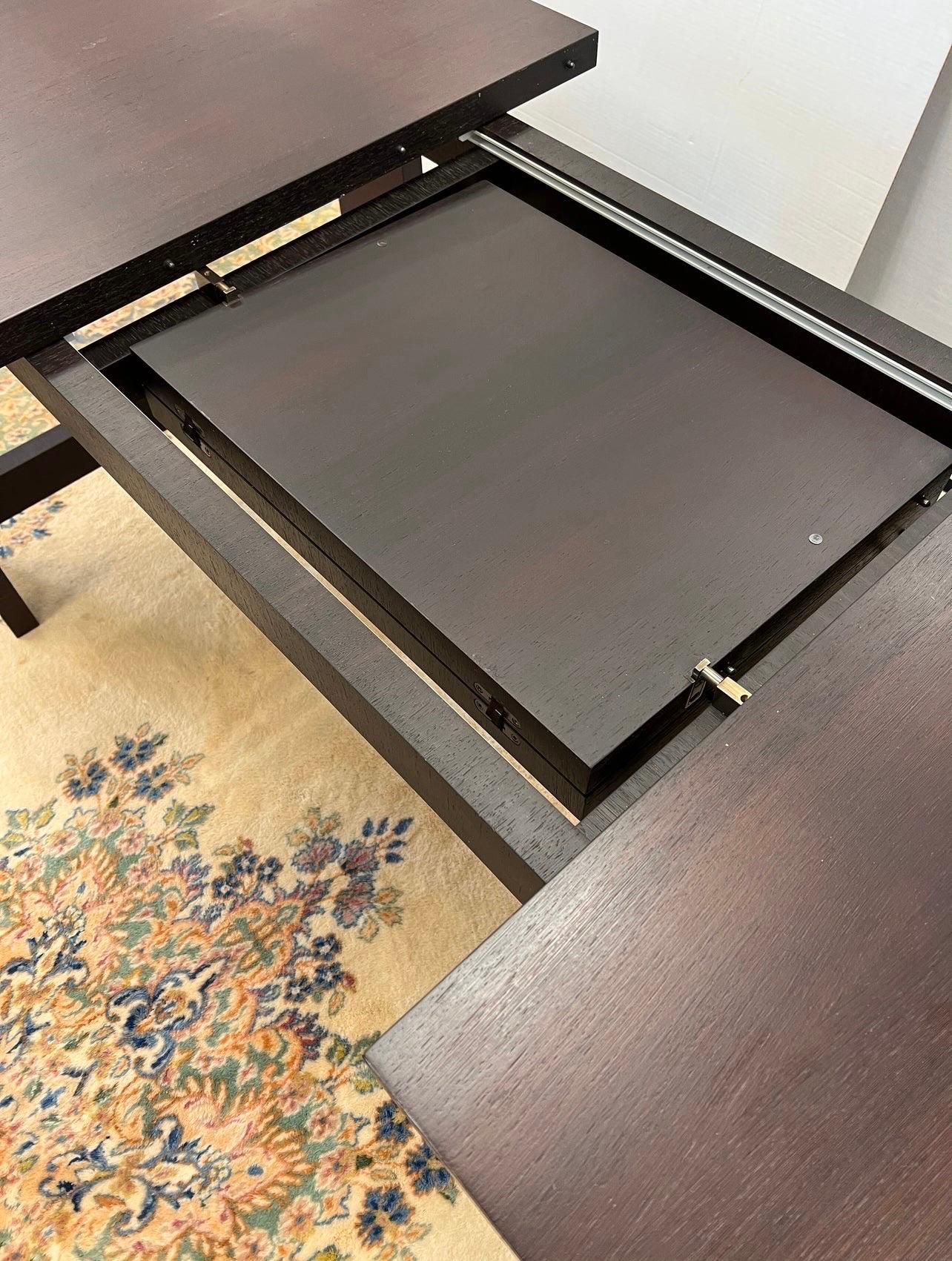 Clean and simple lines define this B&B Italia expandable dining table designed by Antonio Citterio.  The rectangular table has a hidden center leaf underneath that comes up and folds open when the two ends are pulled apart.  Finish is a dark stained