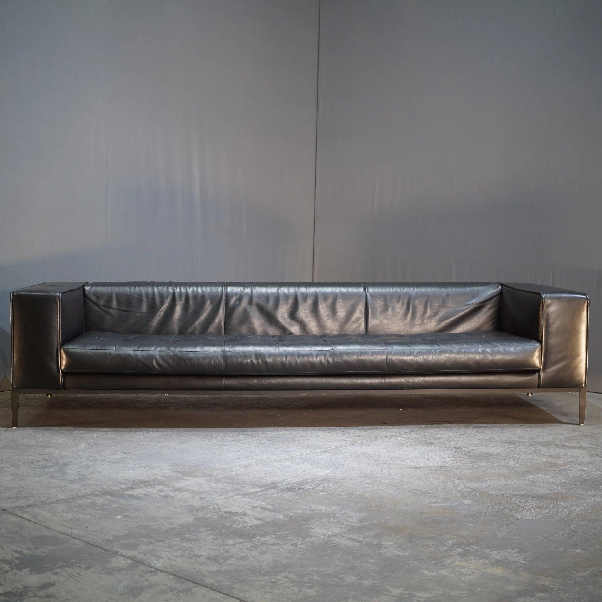 Este sofá de piel negra de B&B Italia, fabricado en 2019, ofrece un diseño elegante y moderno. La piel de alta calidad y las líneas minimalistas hacen que encaje perfectamente en salones contemporáneos. Ideal para añadir elegancia y comodidad a tu