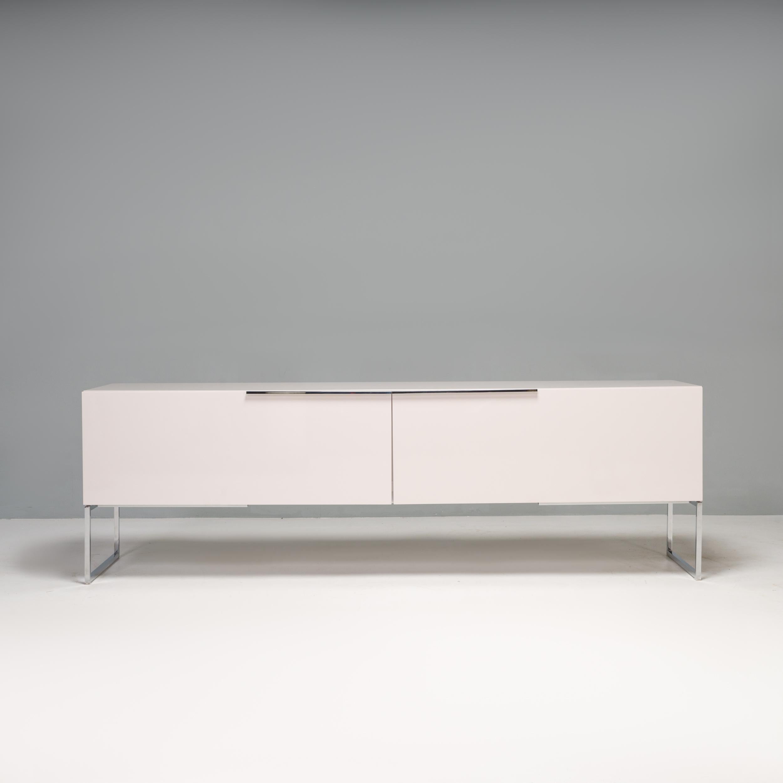 Designed by Paolo Piva for B&B Italia, the Athos sideboard perfectly showcases Piva’s architectural style.

Featuring a glossy white finish, the sideboard has two compartments, sitting on slimline, angular brushed chrome legs.

The sideboard