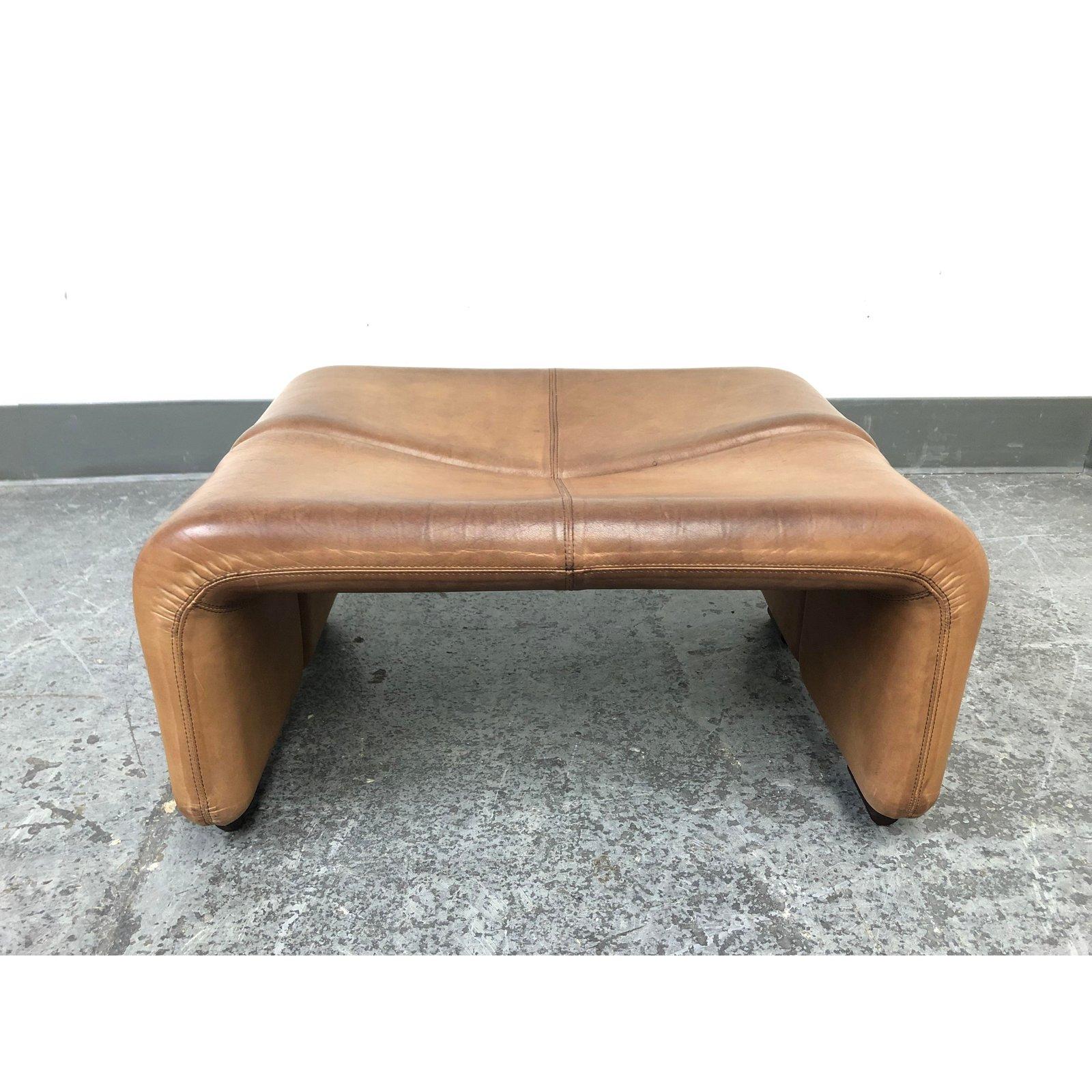 A B&B Italia Coronado Alto leather ottoman. Designed by Tobia and Afra Scarpa in 1966. Originally purchased in the 1980s. Upholstered in original thick cognac leather. Natural distress to the item. The middle surface is slanted, comfortable to