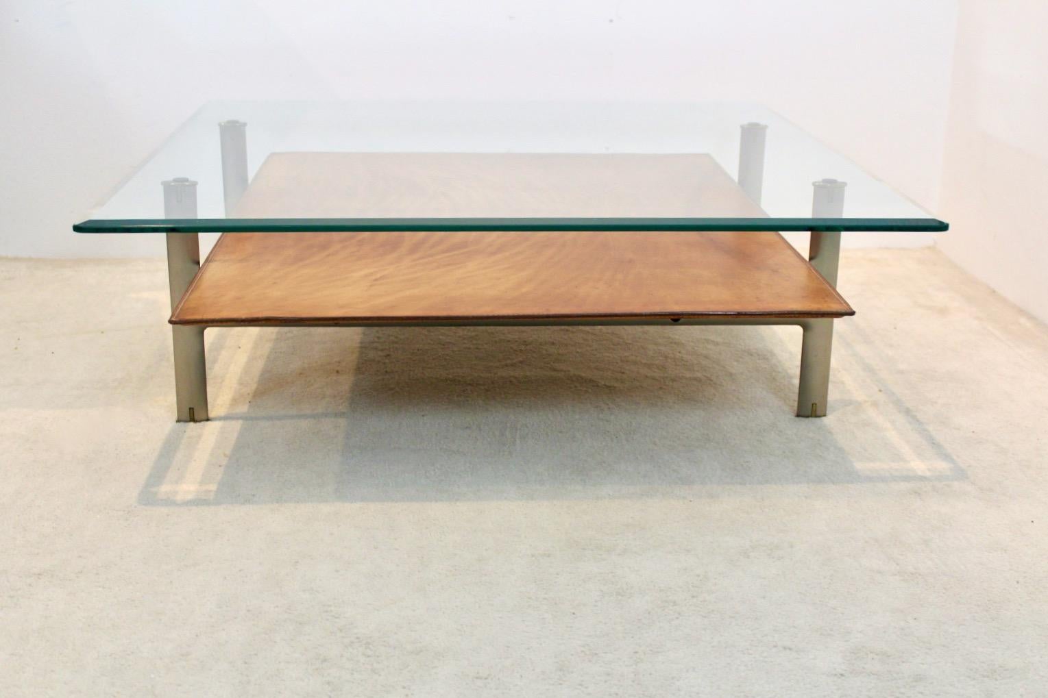 Unique two tier ‘Diesis’ center table designed by Antonio Citterio for B&B Italia in the 1970s. The upper tier is made of solid Glass and the lower tier is made of thick cognac colored leather with beautiful patina. The frame is made of aluminum and