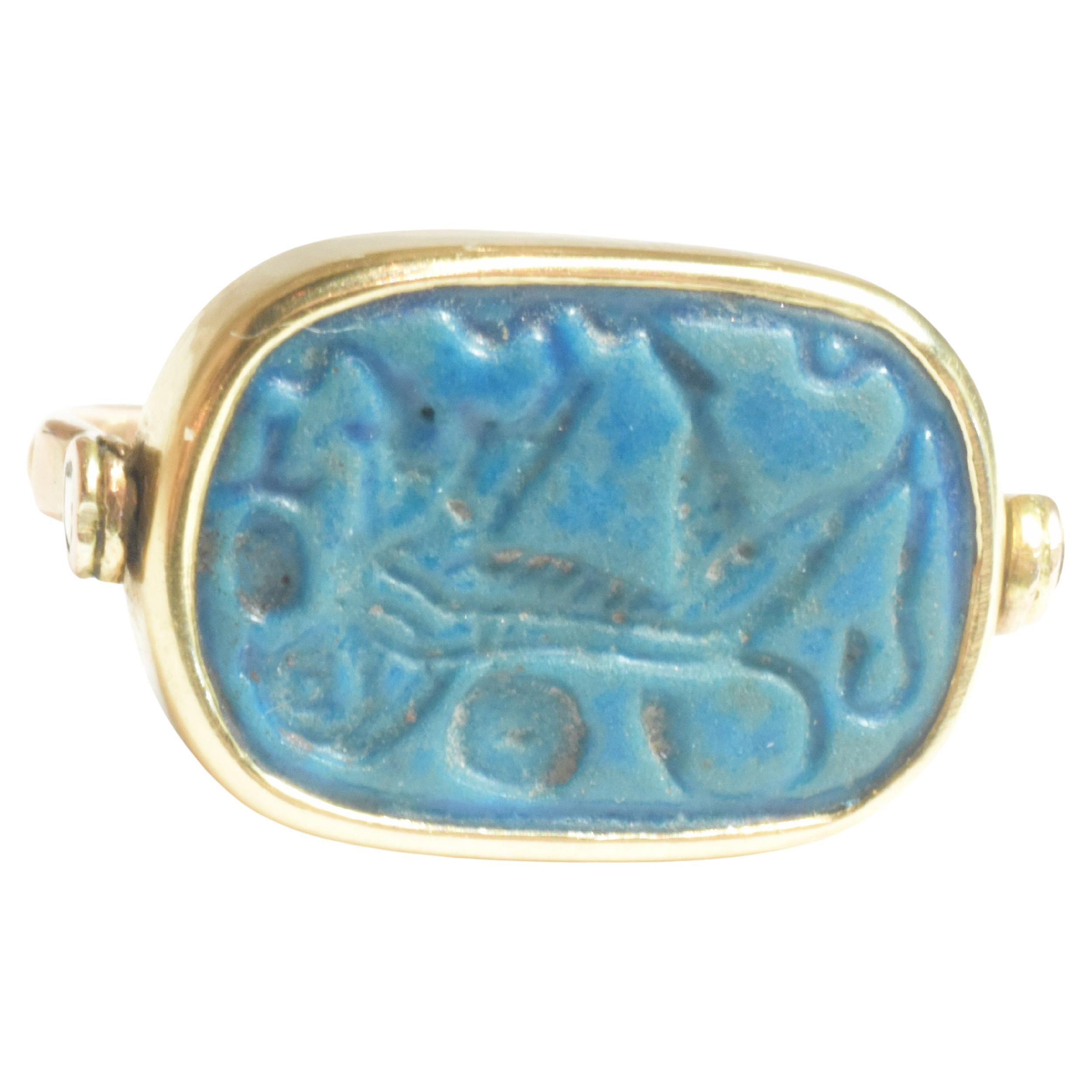 Unique ring comprised of a faience plaque with a cartouche dating to the Middle Kingdom of Egypt. The color of this archaic plaque is striking. The material from which the plaque is made is like ceramic or glass but the center is made of minerals