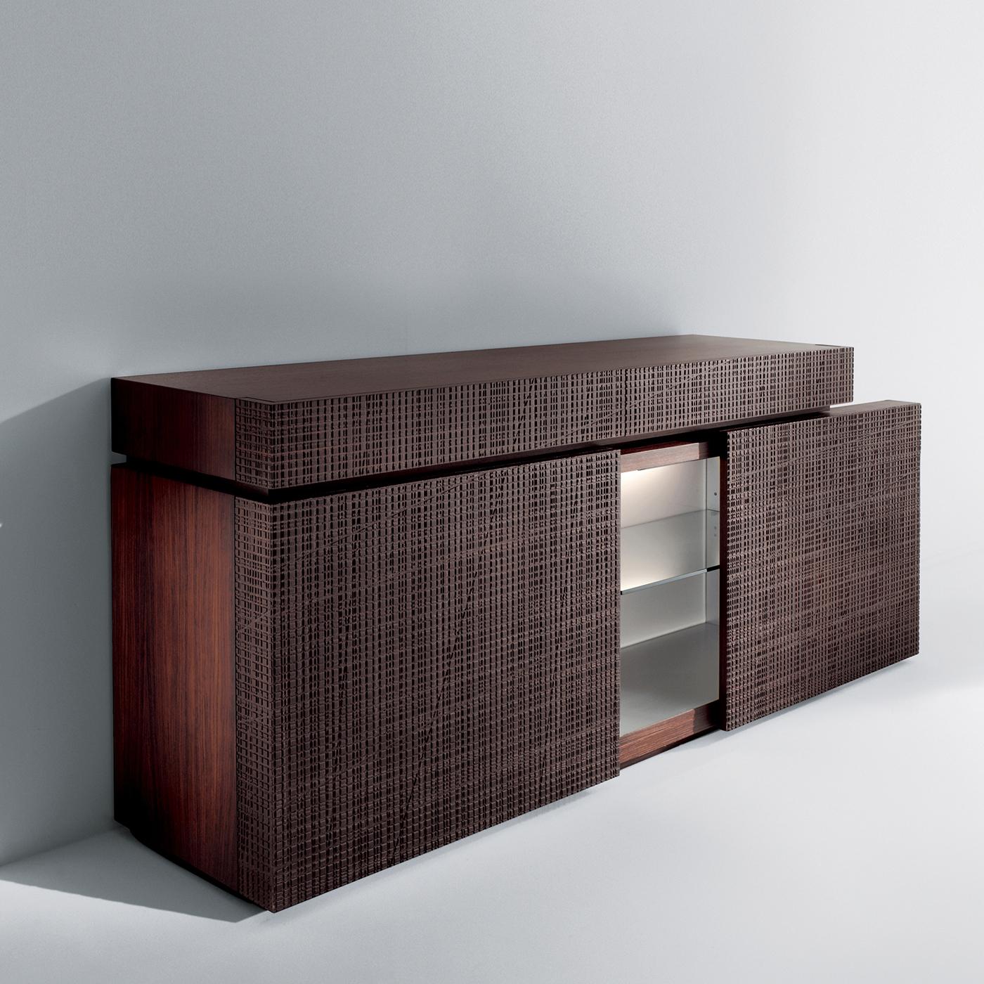 This wooden sideboard features sliding doors, inner glass shelves, lighting, a plexiglass back and drawers carved with a Maxima motif. It features a Rosewood finish, but it can also be made in other finishes and dimensions on request. A striking,