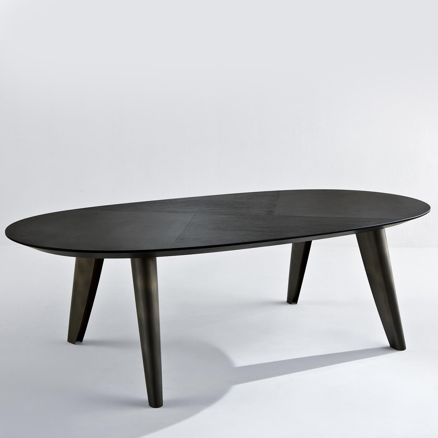 This oval-shaped dining table in dark stone oak wood is unique as it features a cross-grain pattern on the table top. The legs supporting the table are in dark brass with a tobacco finish and are set at a slight angle. A beautiful table for those in