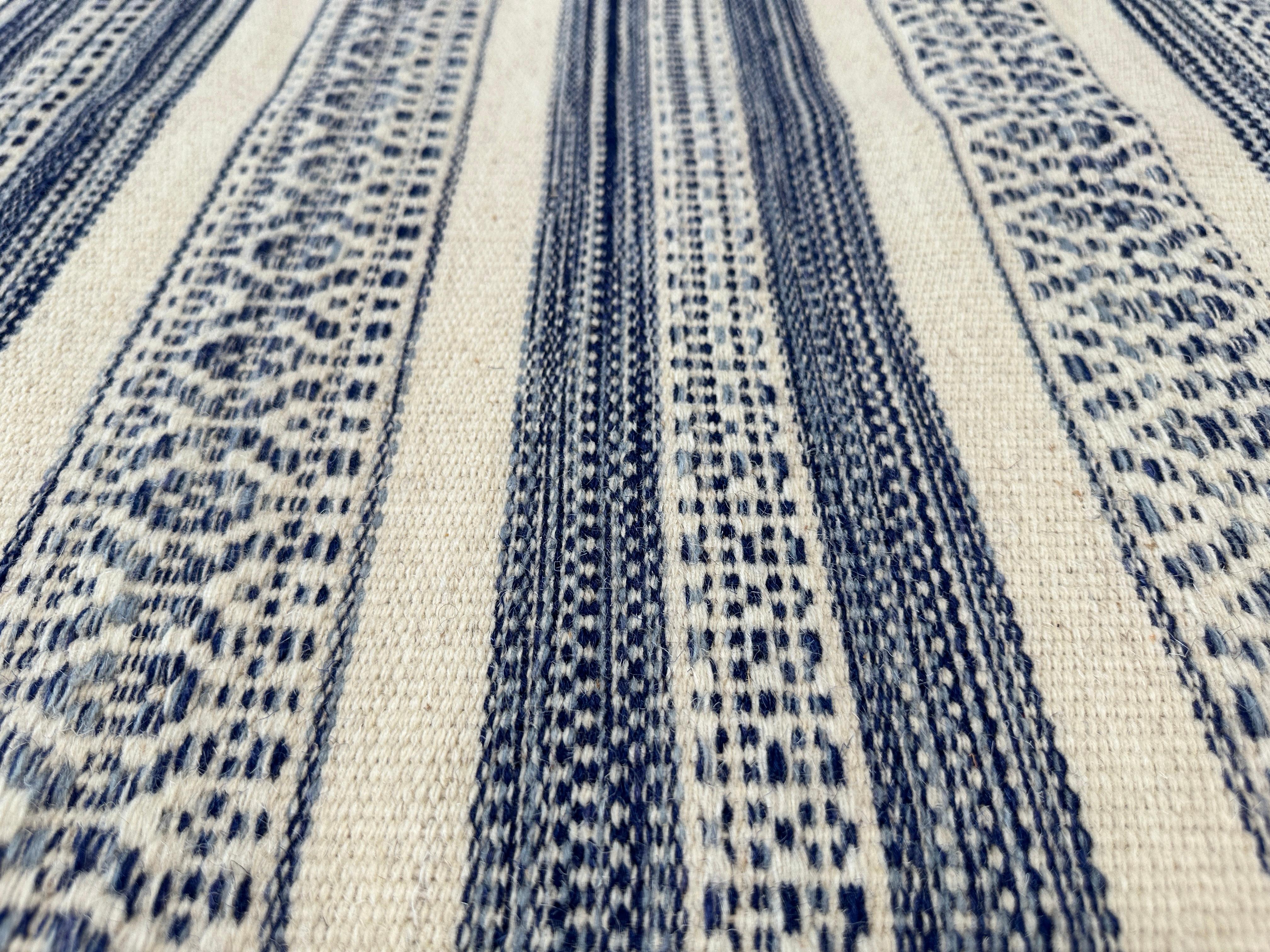 Trasforma la tua casa o la tua casa al mare con l'eleganza senza tempo di questo tappeto kilim tessuto a mano. Realizzato da abili artigiani, questo tappeto 8x10 presenta un sorprendente motivo a strisce bianche e blu che evoca la serena bellezza