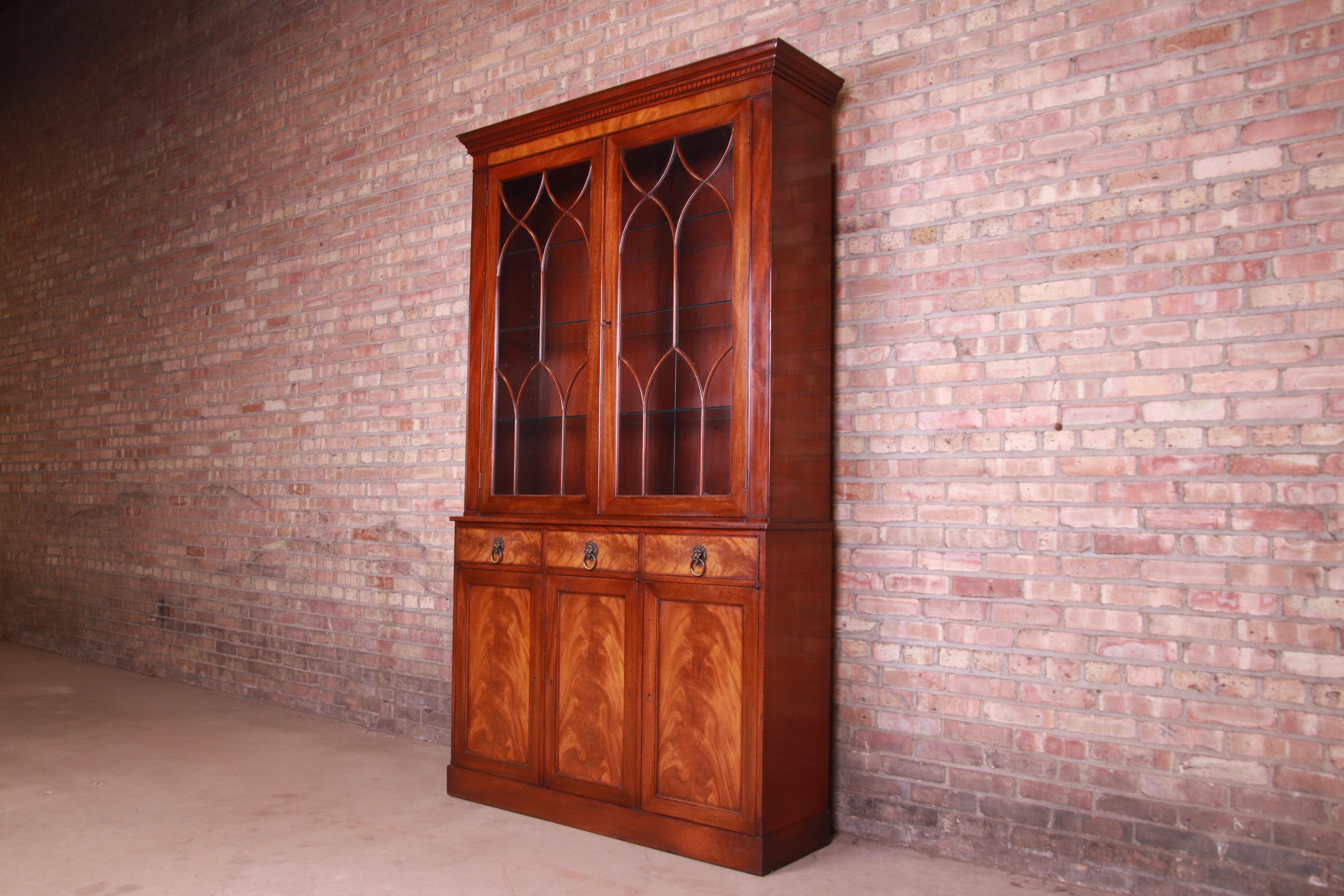 A gorgeous Georgian style breakfront bookcase, display cabinet, or dining cabinet

By Beacon Hill Collection

USA, Mid-20th Century

Book-matched flame mahogany, with brass lion head ring pulls and mullioned glass front doors. Cabinet locks,